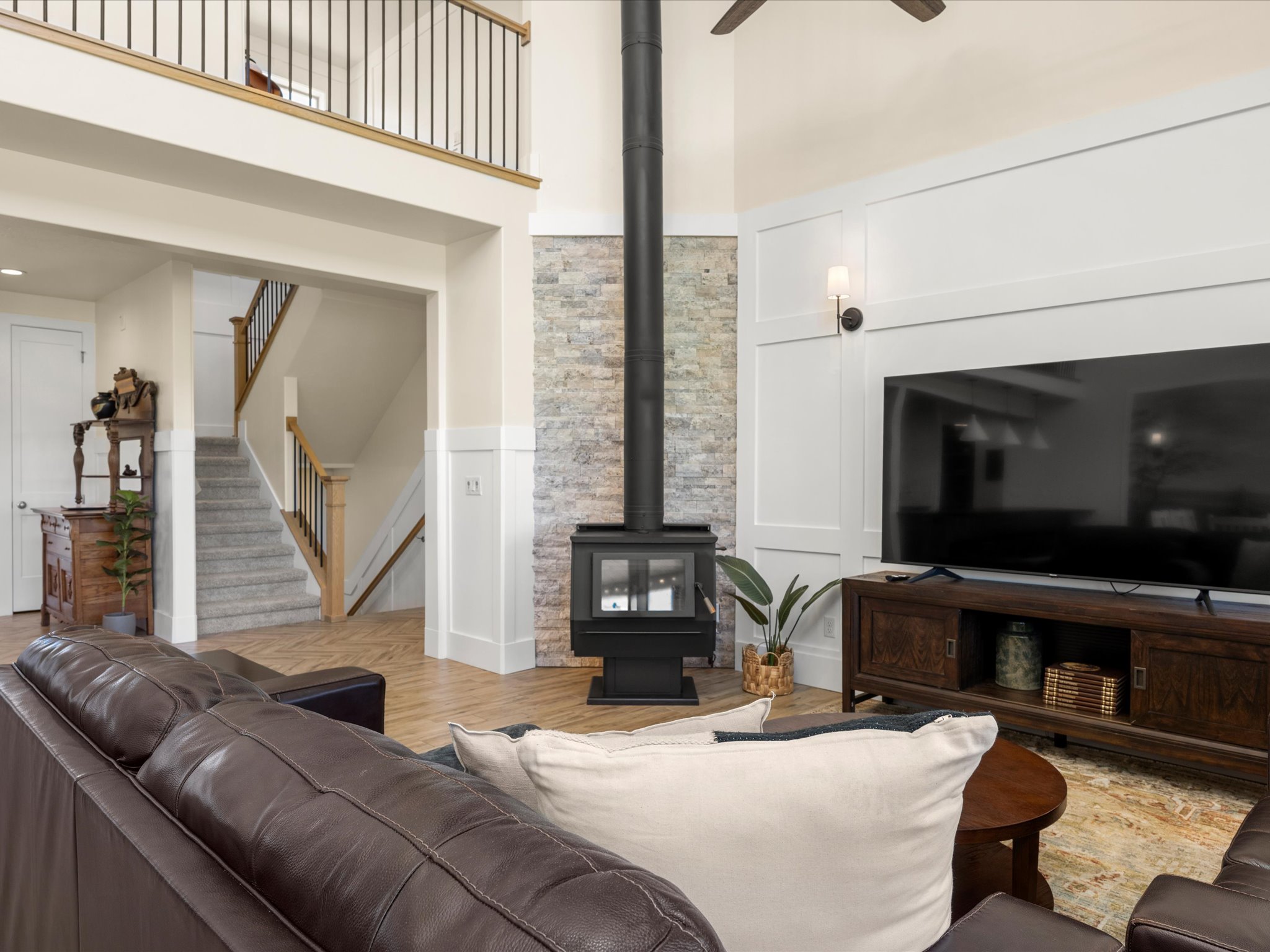 Living area featuring a floor-to-ceiling brick-clad fireplace with a black wood-burning stove, high ceilings, and light wood-finish tile flooring
