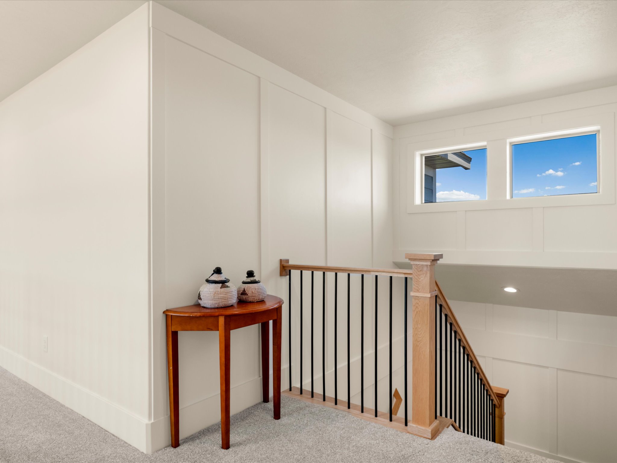 Upper-level landing featuring board and batten wall detailing, light carpeting, and dual high windows
