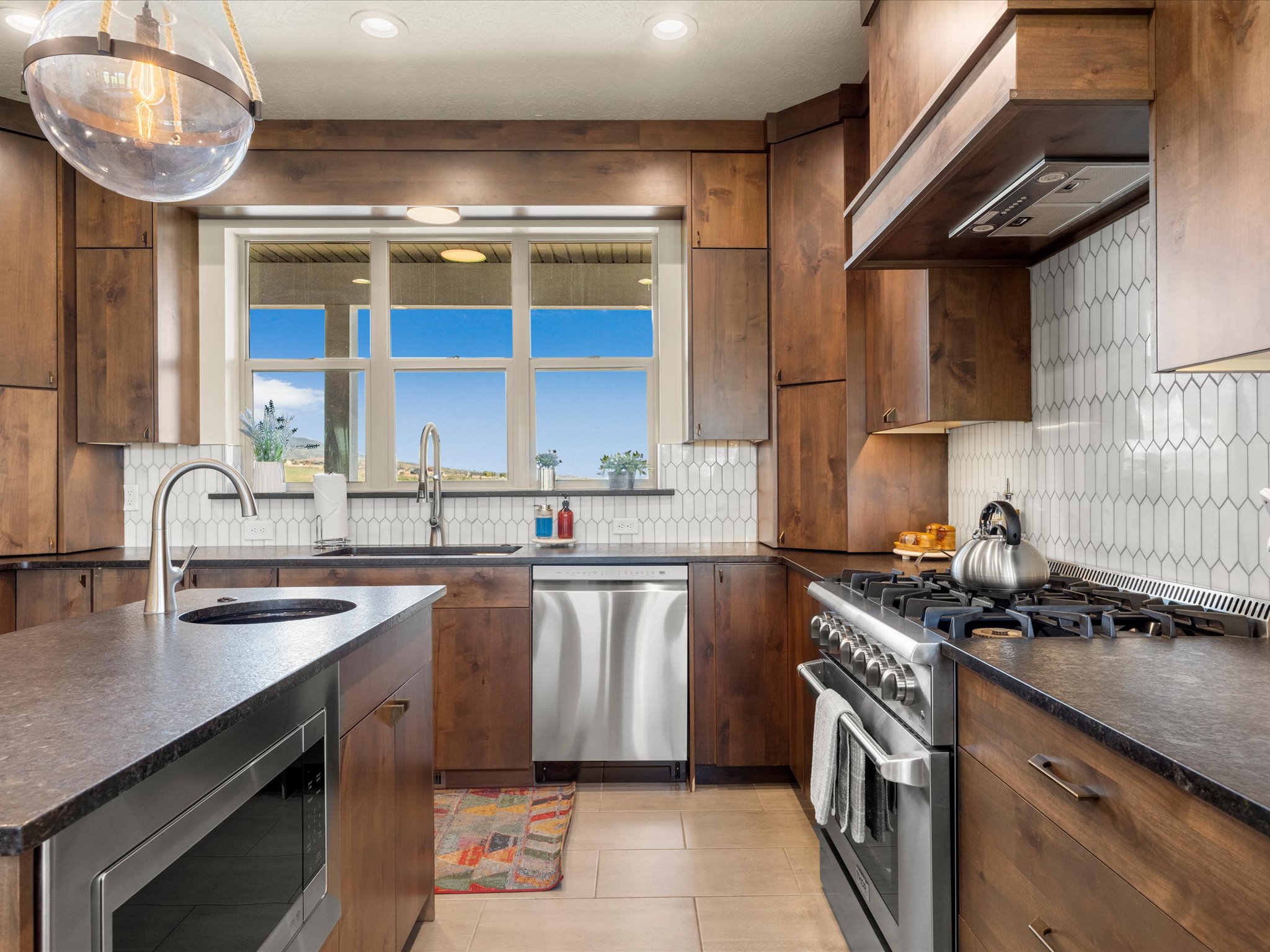 Kitchen with rich wood cabinetry, stone countertops, and a white picket tile backsplash