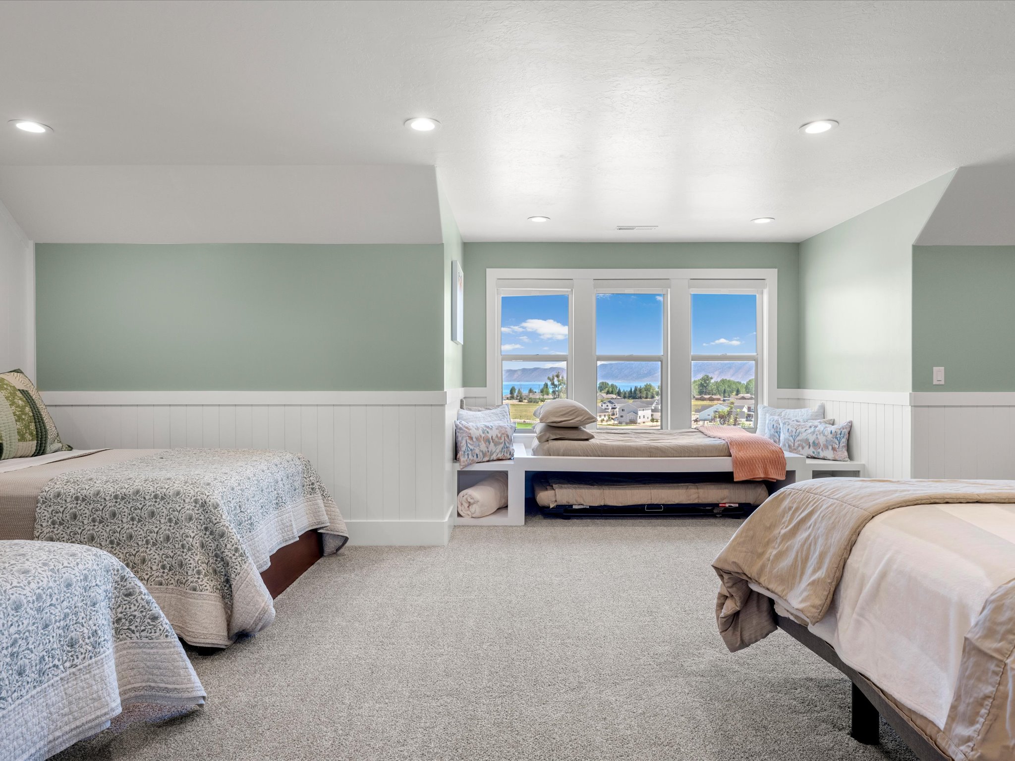 Expansive bonus room featuring a window bench with integrated storage, recessed lighting, wall paneling, and soft carpet flooring