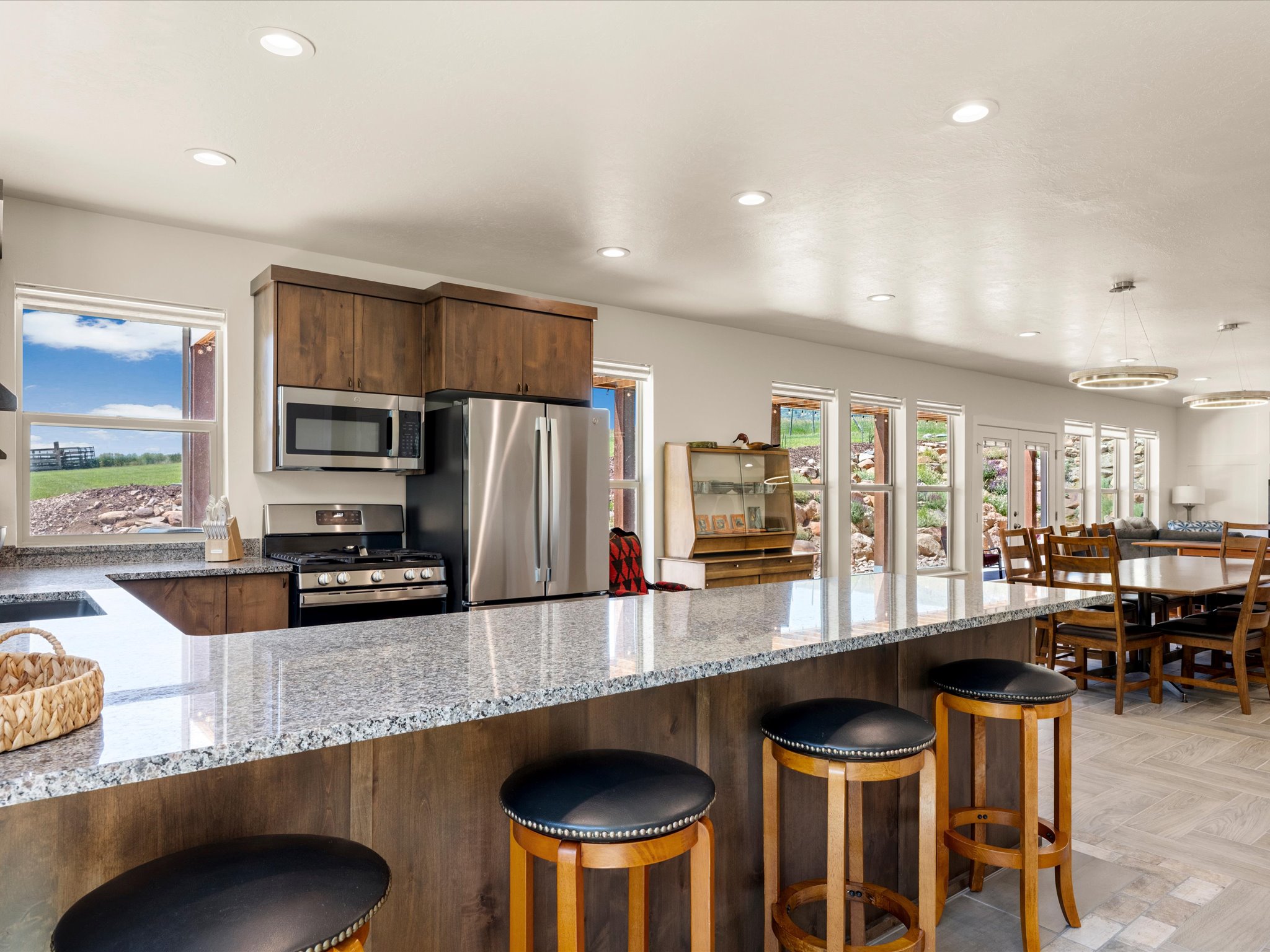 Kitchen featuring a spacious island with seating, stainless steel appliances, dark wood cabinetry, light-toned countertops, and recessed lighting
