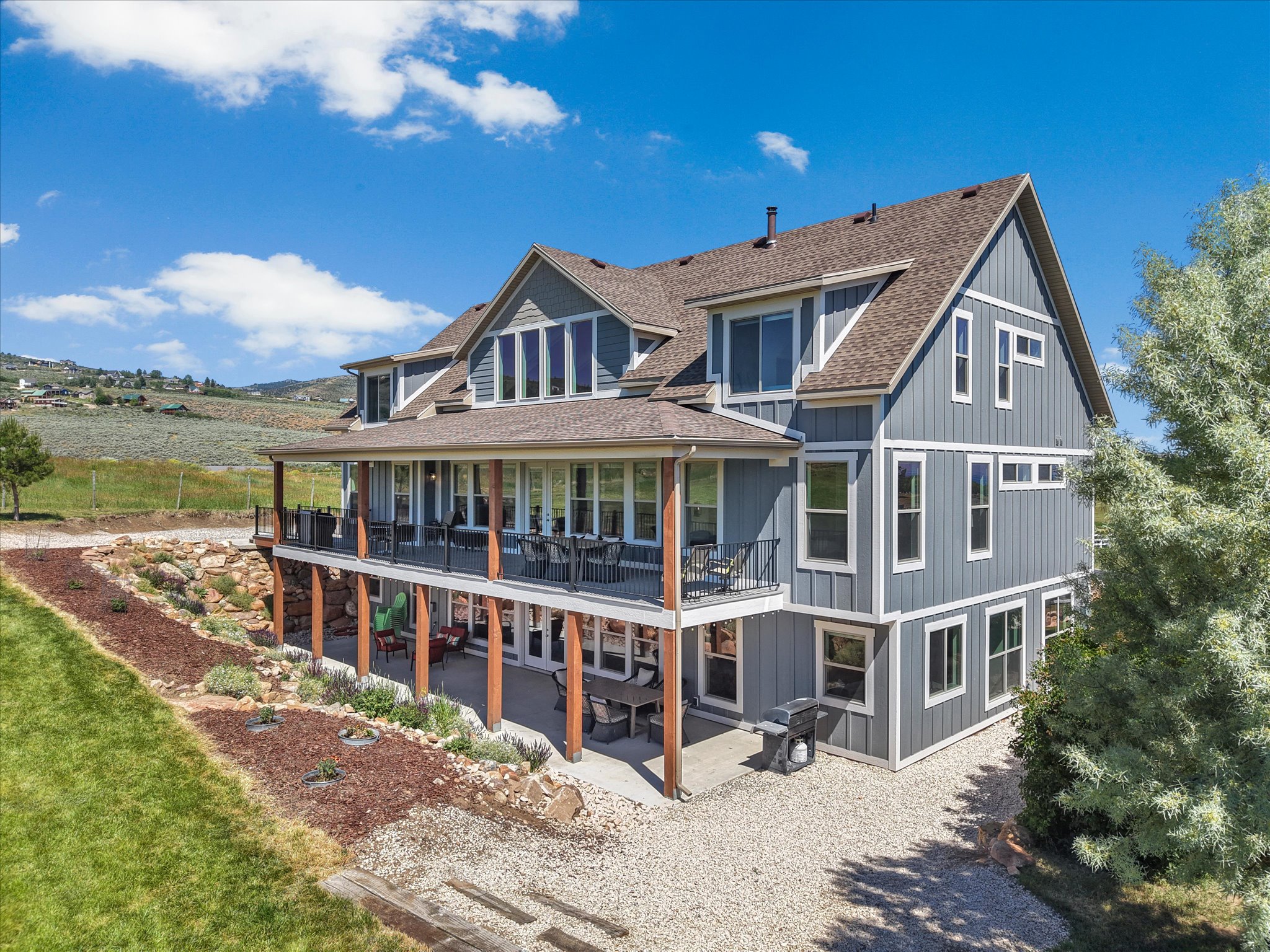 Multi-level residence featuring gray board and batten siding, white trim, and a covered upper-level deck