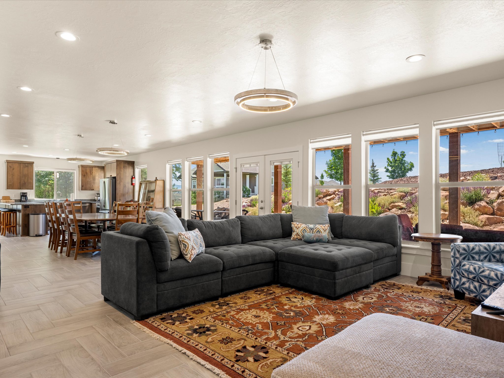 Open-concept living space featuring light wood-finish flooring in a herringbone pattern and multiple recessed light fixtures