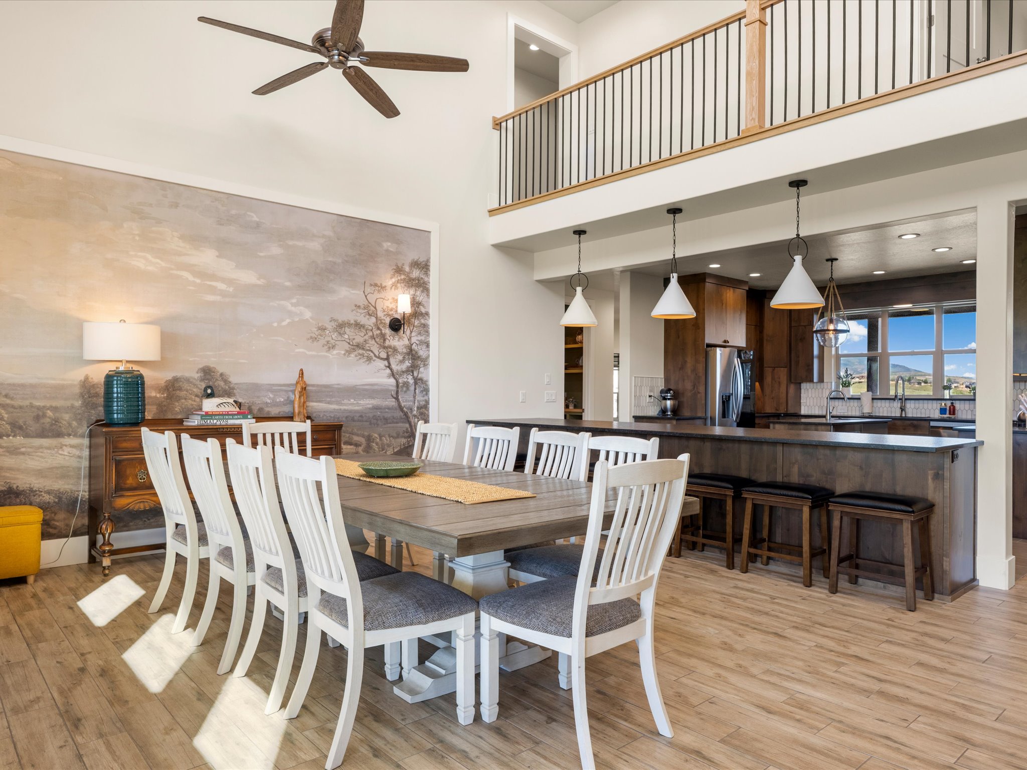Dining area featuring a vaulted ceiling with a ceiling fan, wood-finish tile flooring, and a decorative mural wall