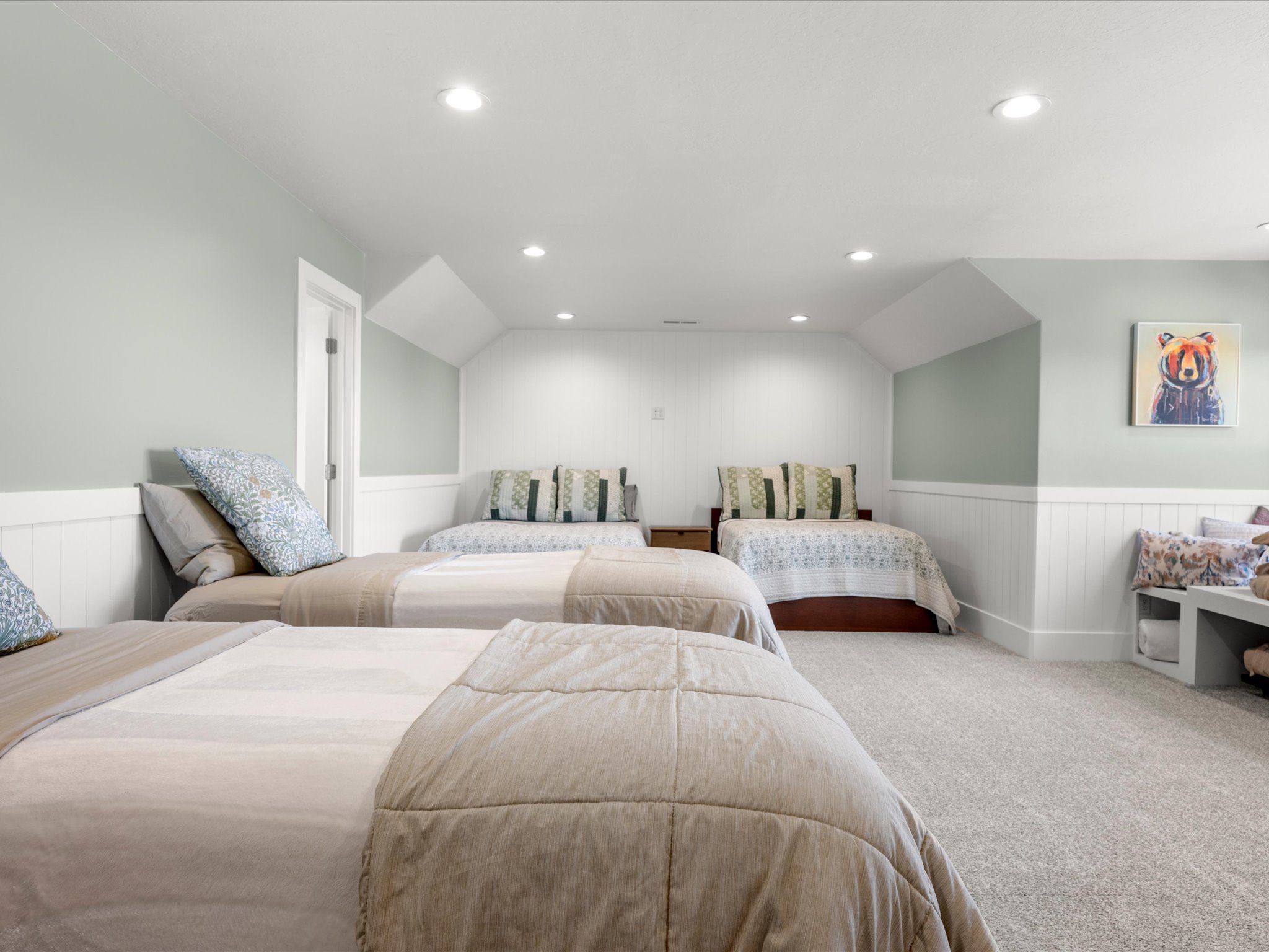 upstairs bonus room currently used as a  bedroom featuring white wainscoting, recessed lighting, and soft green wall accents