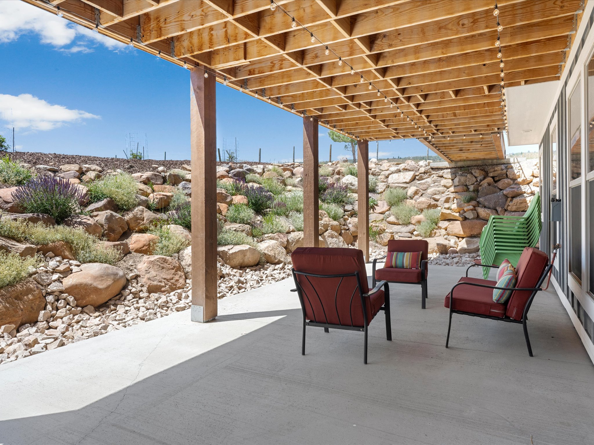 Covered outdoor patio with a concrete surface, supported by exposed wood beams