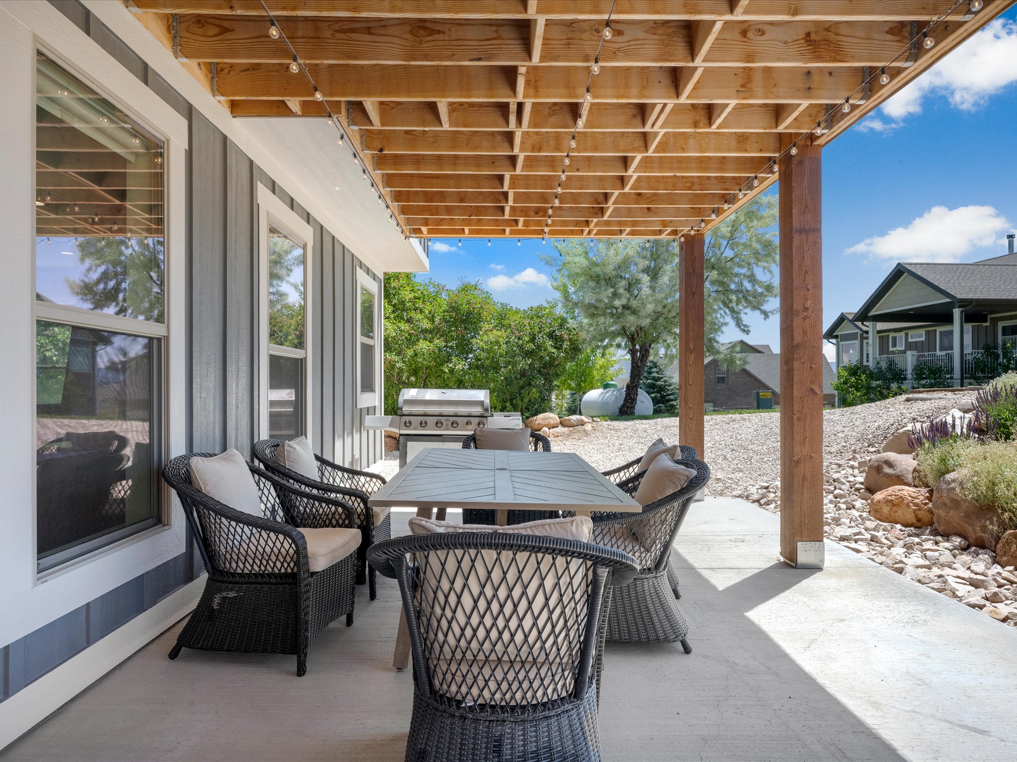 Covered patio featuring a concrete surface, exposed wood beam ceiling, and string lighting