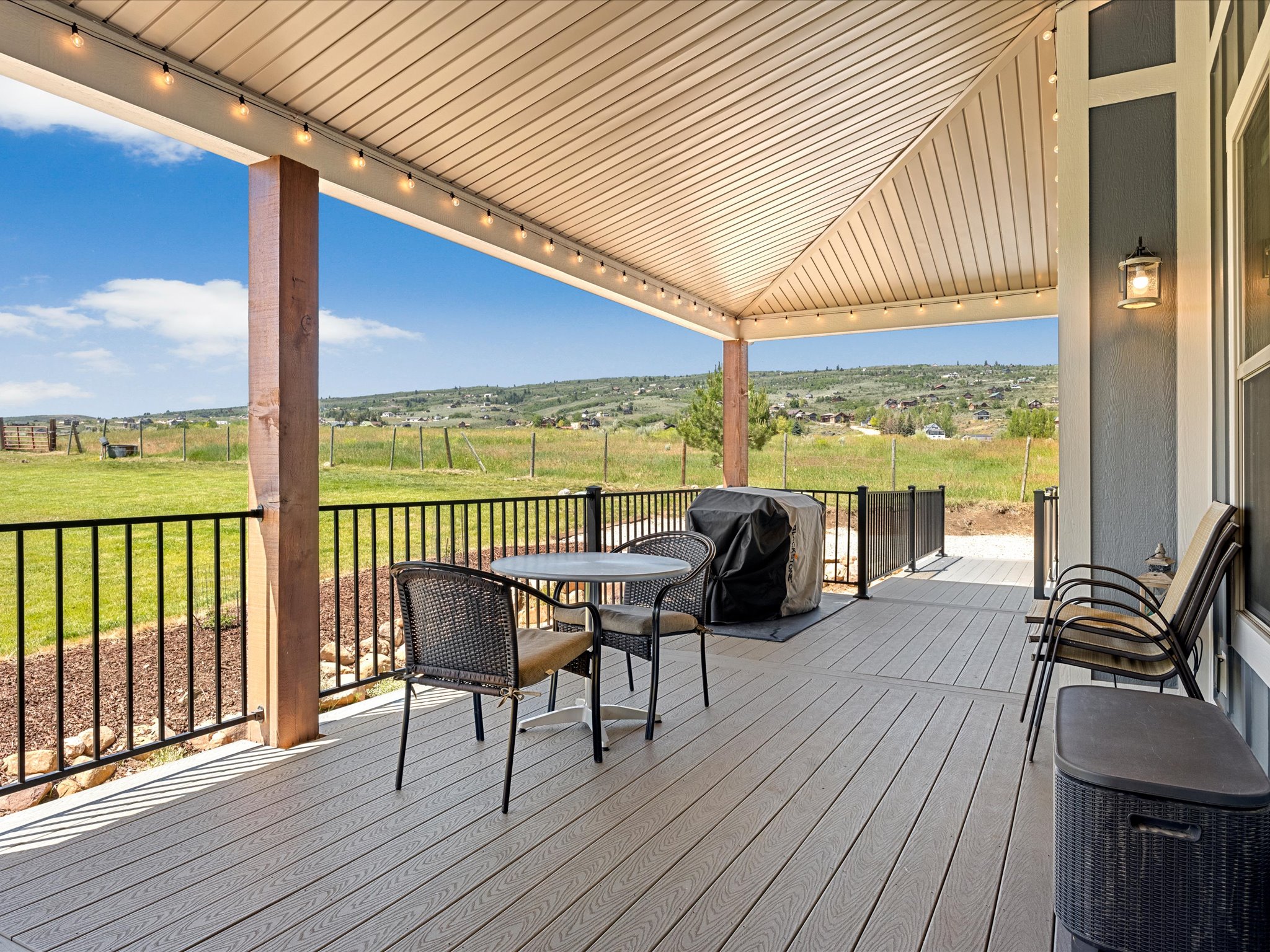 Covered outdoor patio featuring composite decking, recessed lighting, and black metal railing