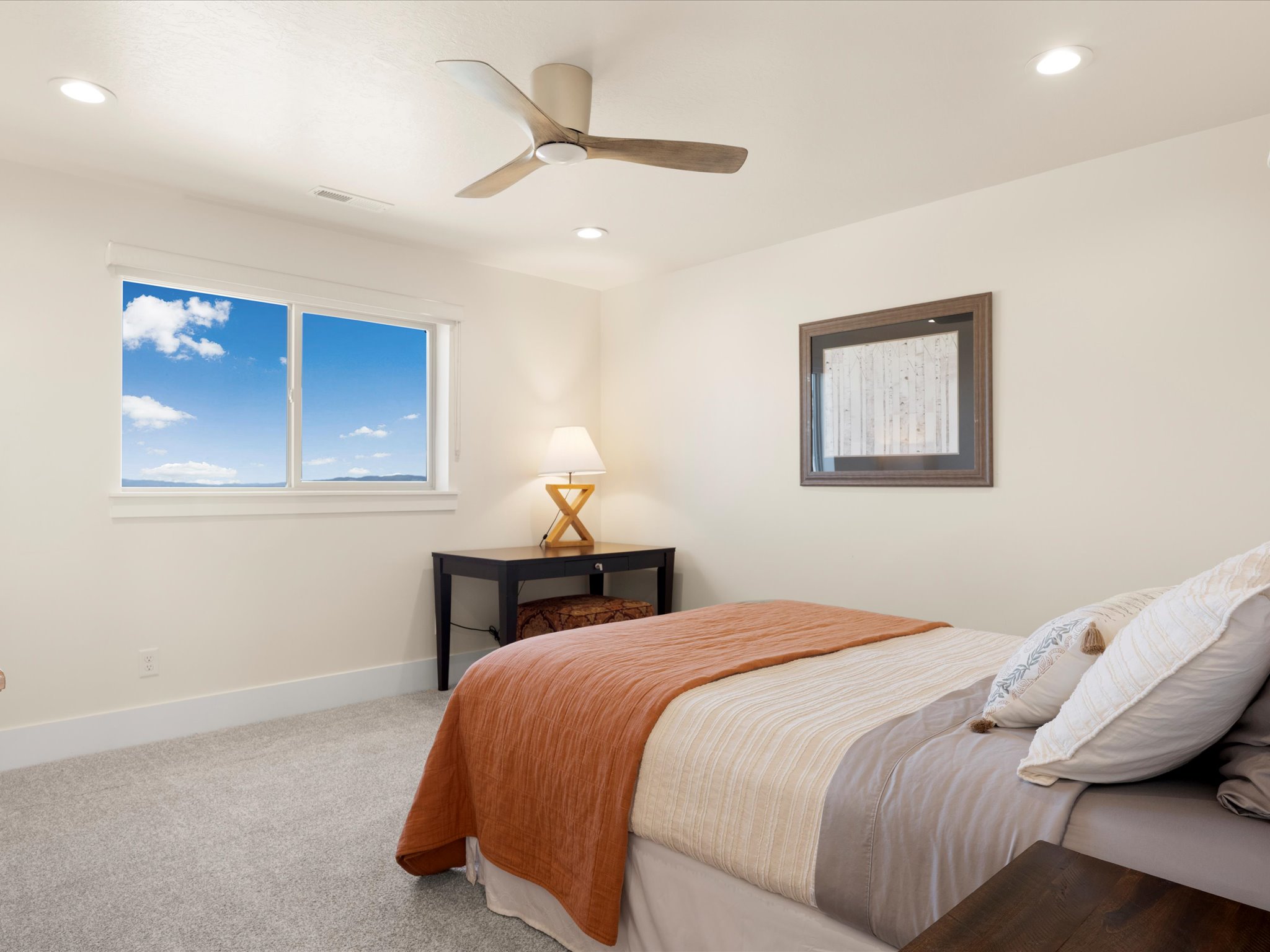 Carpeted interior space featuring a window with a distant landscape, recessed ceiling lighting, and a ceiling fan with light-toned blades