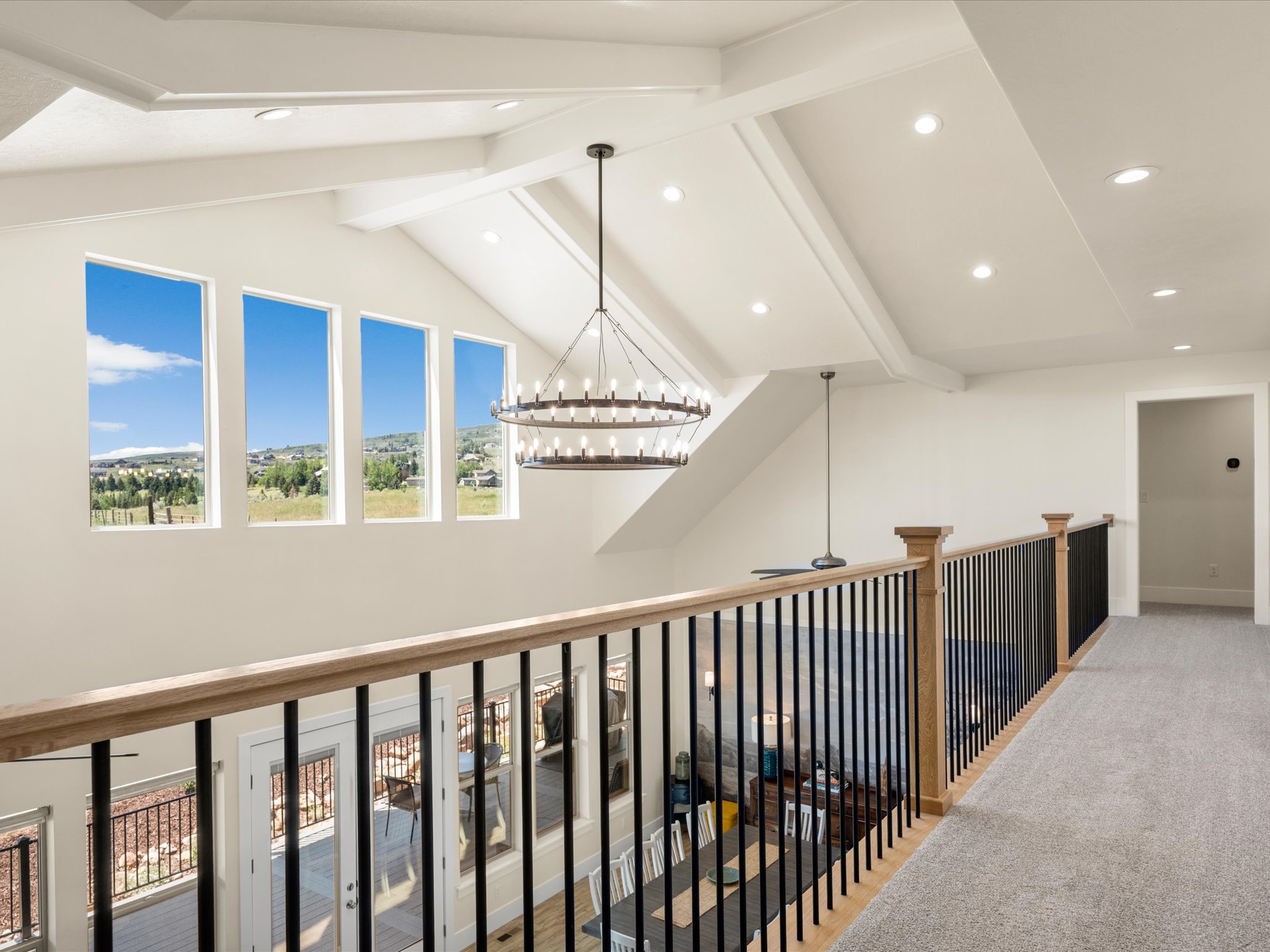 Upper-level hallway with carpet flooring and a wood handrail with black metal balusters