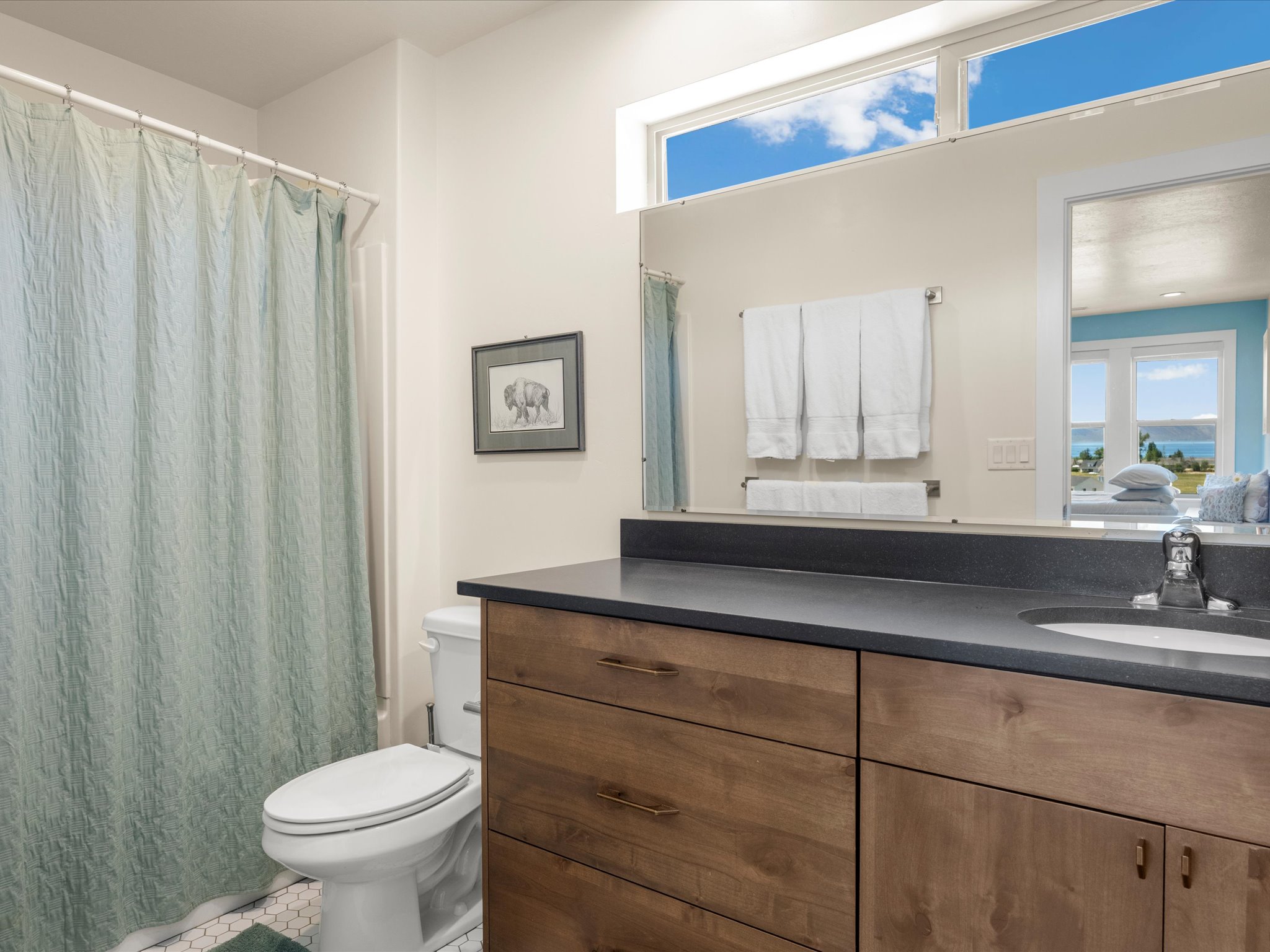 Bathroom featuring a wood-finish vanity with drawer storage, dark countertop, and integrated sink