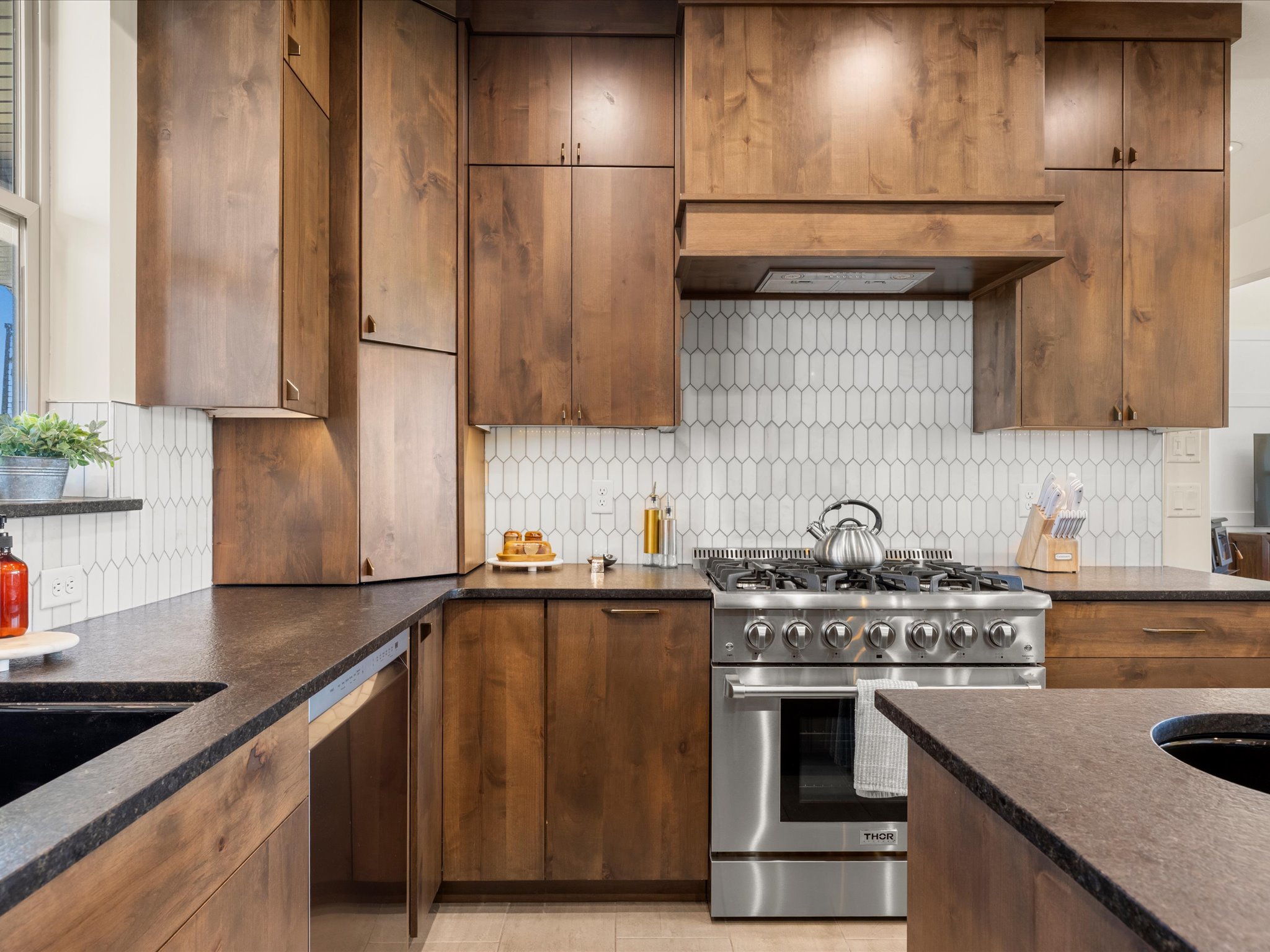 Kitchen featuring wood cabinetry, dark countertops, a stainless steel range, a coordinating range hood, and a white picket-style tile backsplash