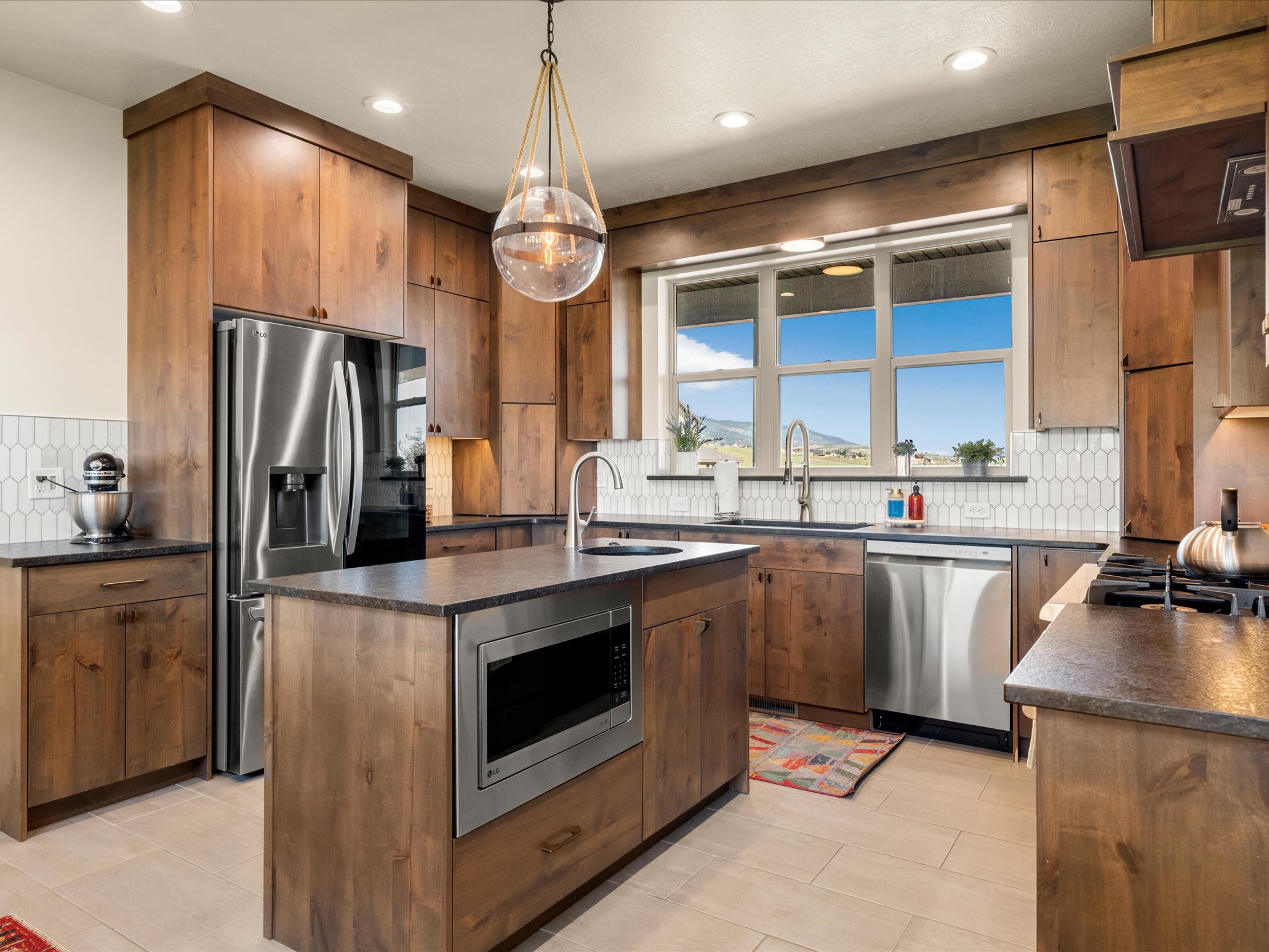 Modern kitchen featuring warm wood-finish cabinetry, stainless steel appliances, and a central island with a built-in microwave
