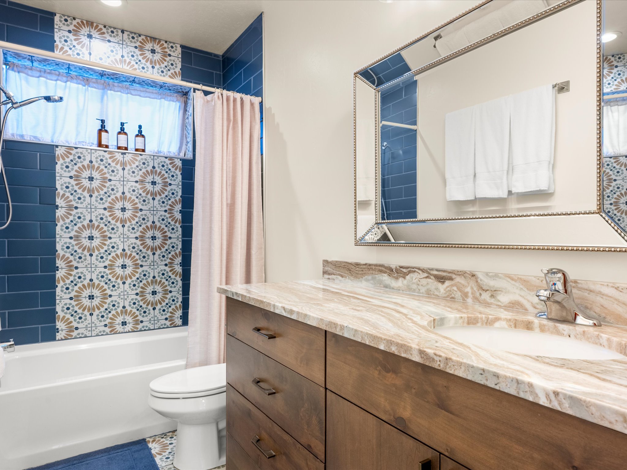 Bathroom featuring a wood-finish vanity with a single basin and a polished stone countertop