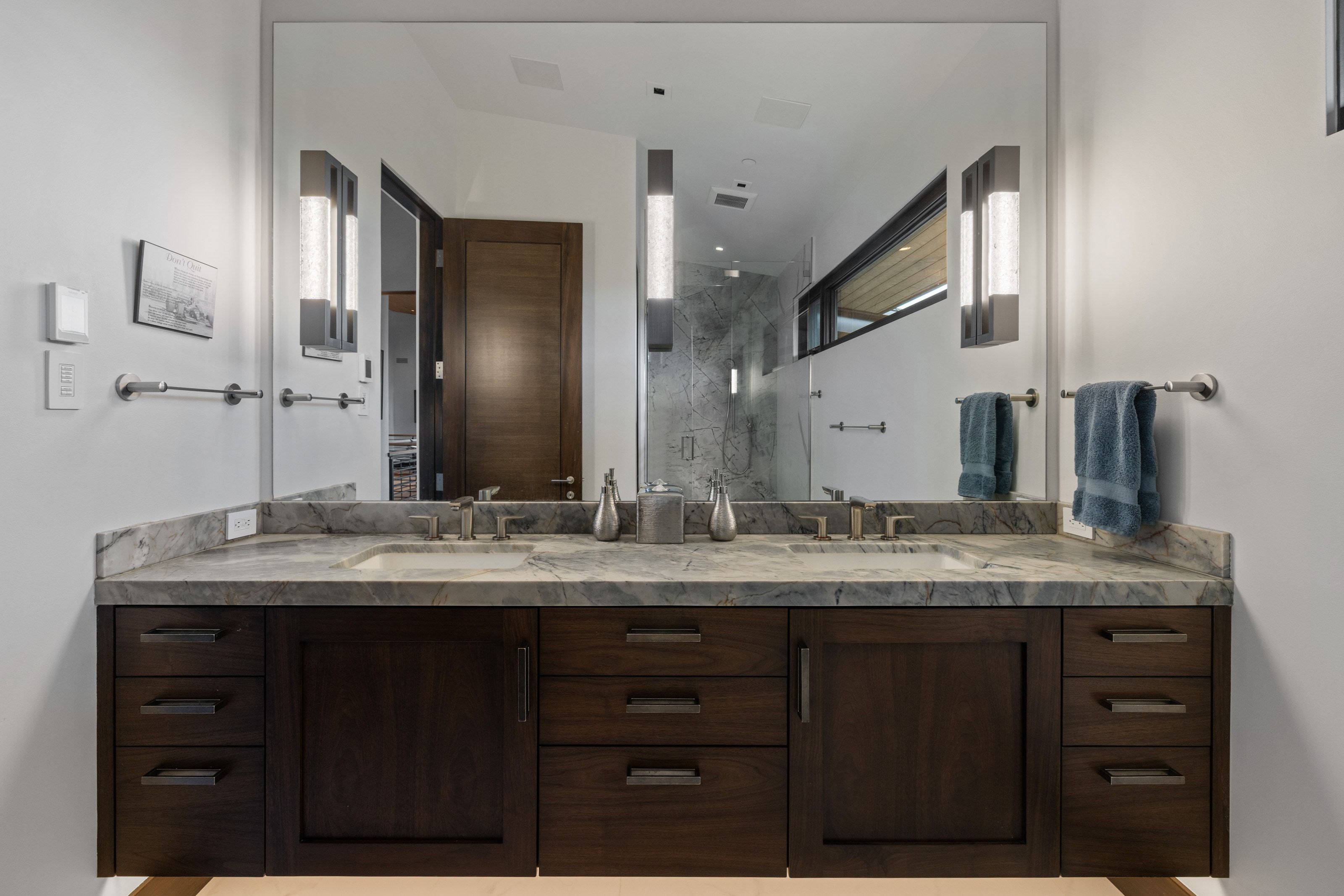 Double vanity with integrated sinks, a stone countertop, and dark wood-finish cabinetry