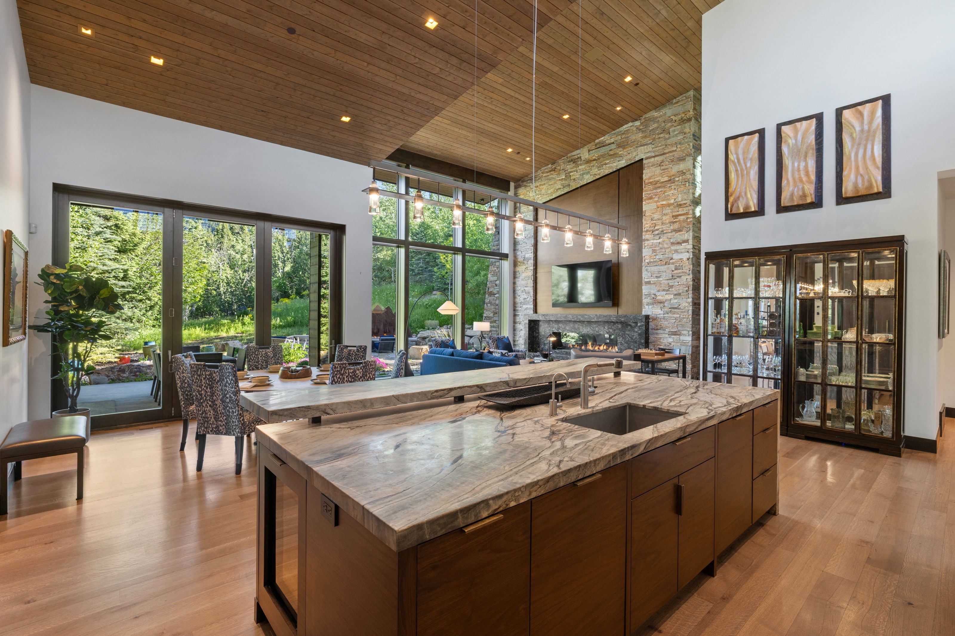 Gourmet kitchen island with an undermount sink and stone countertop, rich wood-finish cabinetry, and light wood-finish flooring