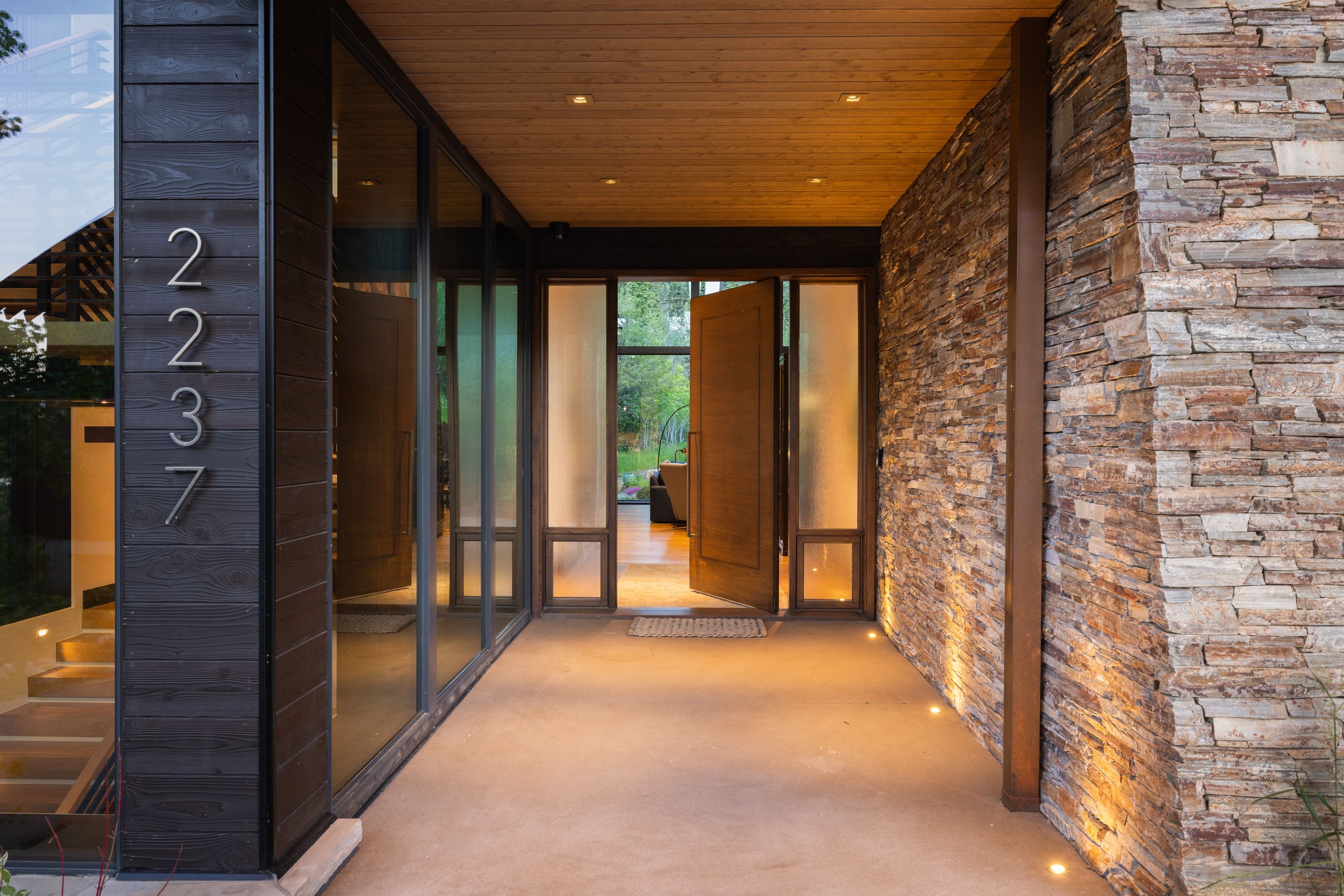 Entryway featuring a stacked stone accent wall, large floor-to-ceiling windows, rich wood-paneled ceiling, and integrated recessed lighting