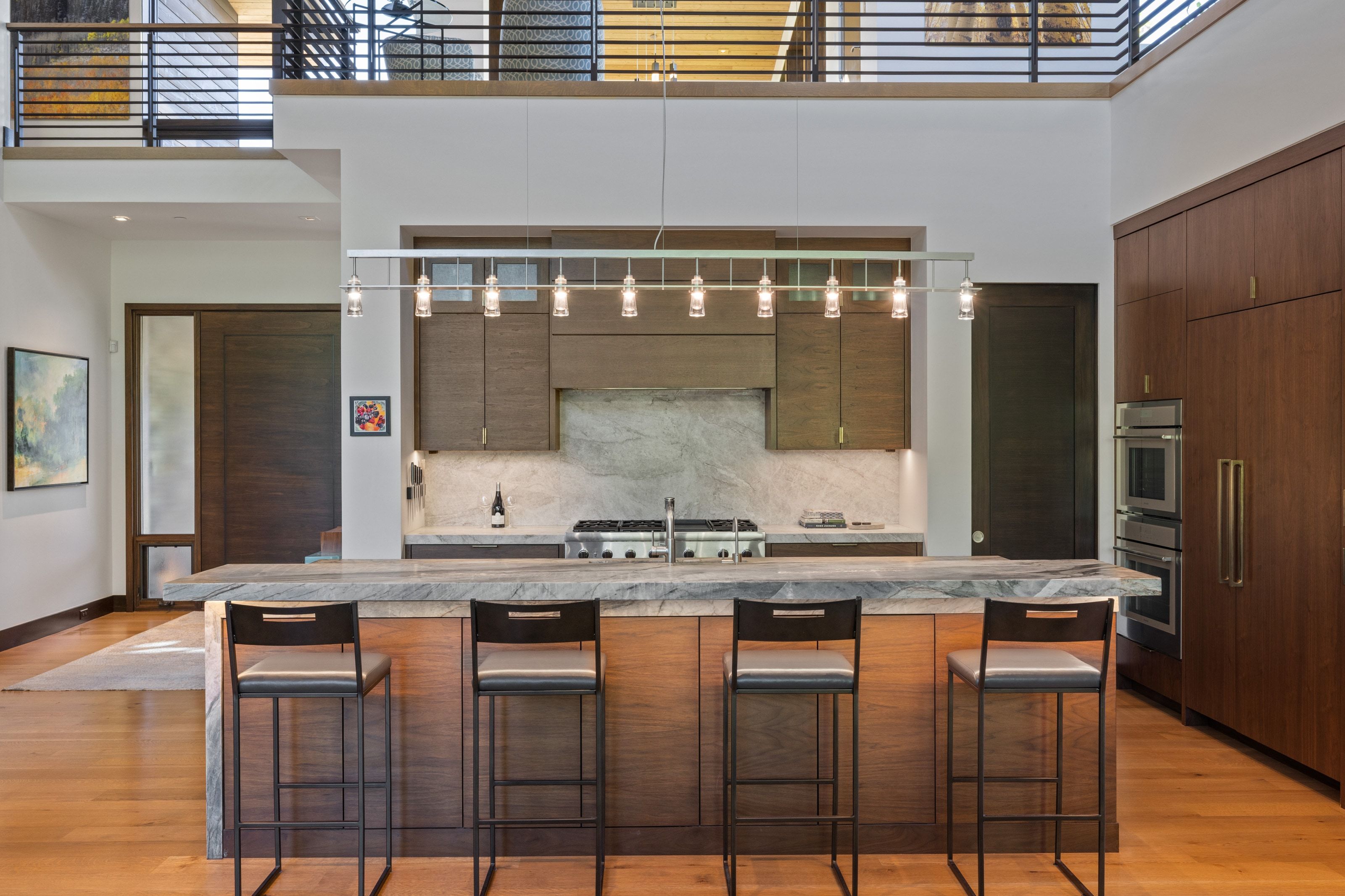 Gourmet kitchen featuring a large island with seating, a gas range with a stone backsplash, integrated double ovens, and extensive wood-finish cabinetry