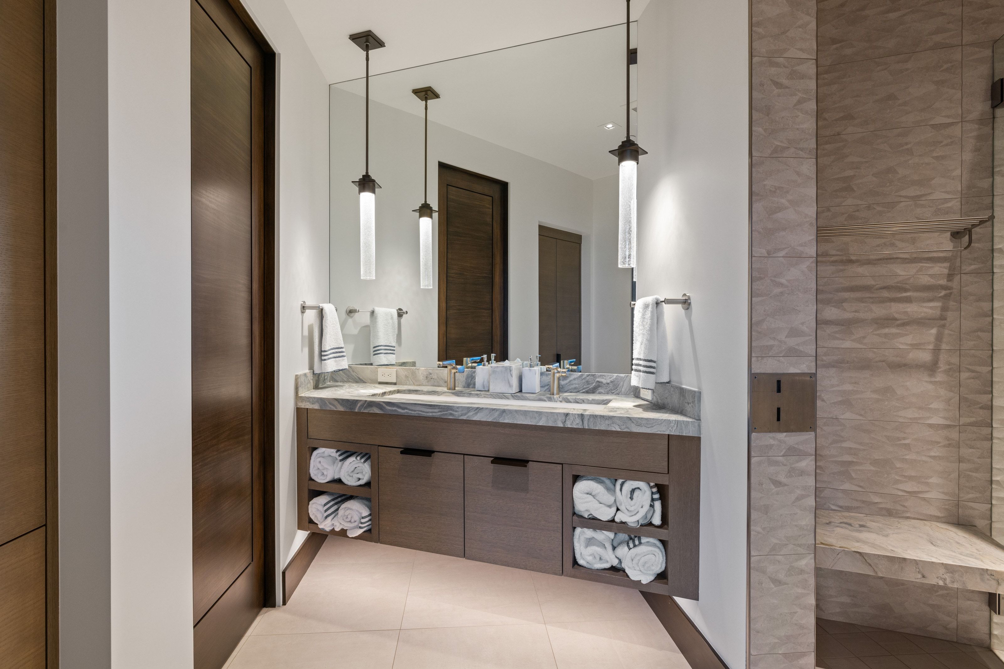 Dual pendant lighting illuminates a double vanity with a stone countertop