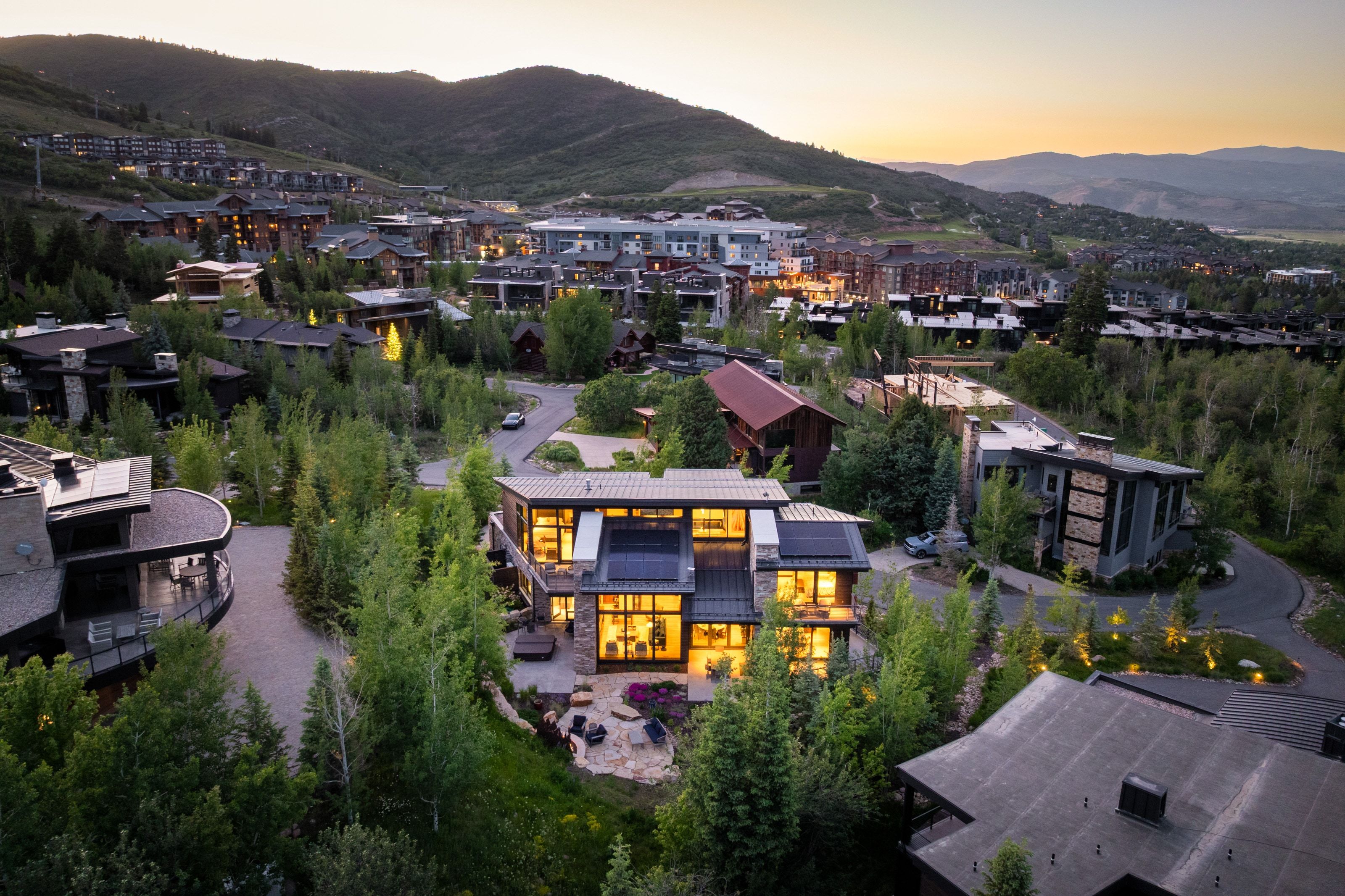 Contemporary home with extensive glass facade, multiple outdoor terraces, integrated lighting, and a stone patio