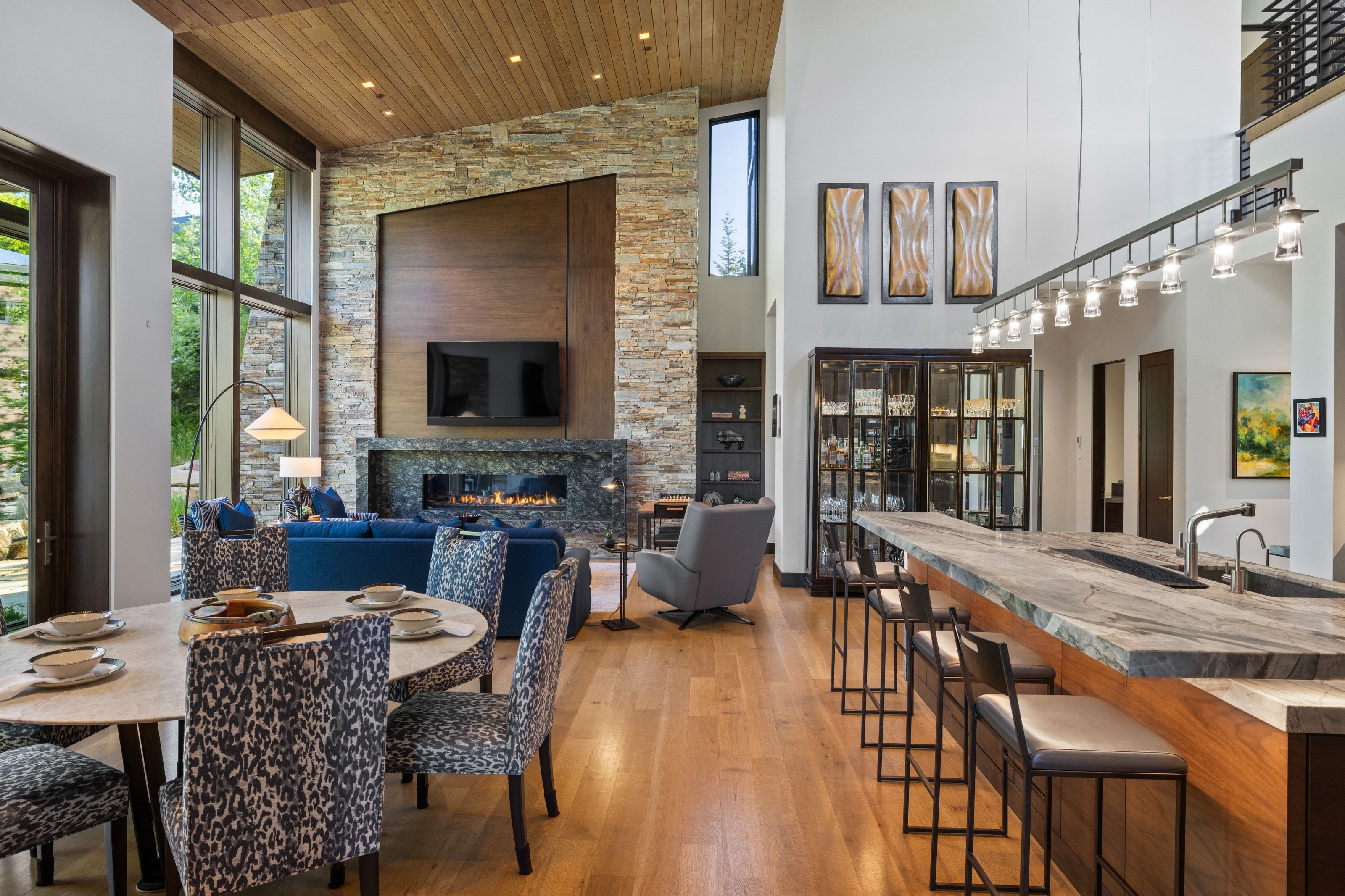 Open-concept living space featuring a stone accent wall, linear fireplace, and expansive windows