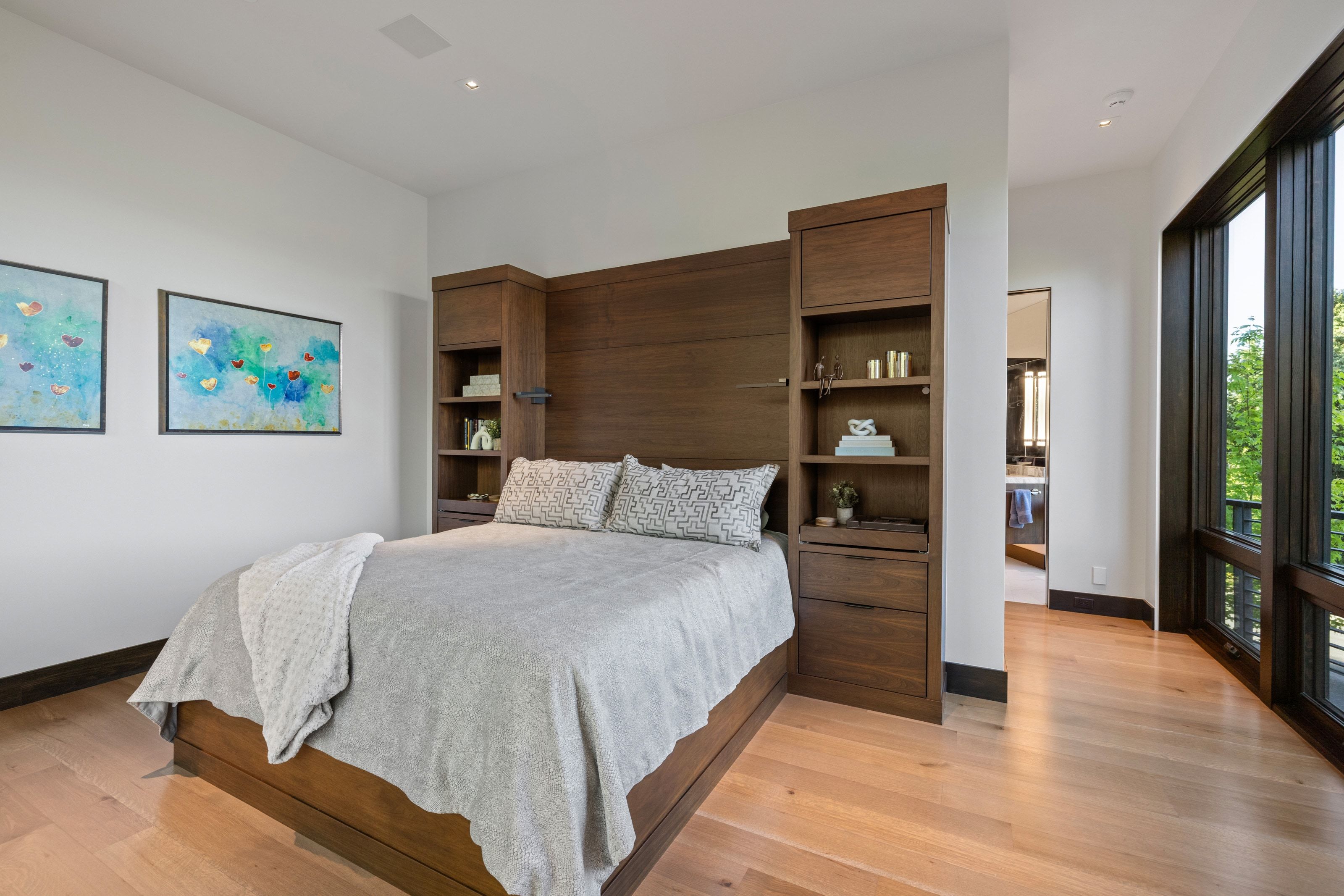 Light wood-finish flooring complements a built-in wood bed frame with integrated shelving and drawers