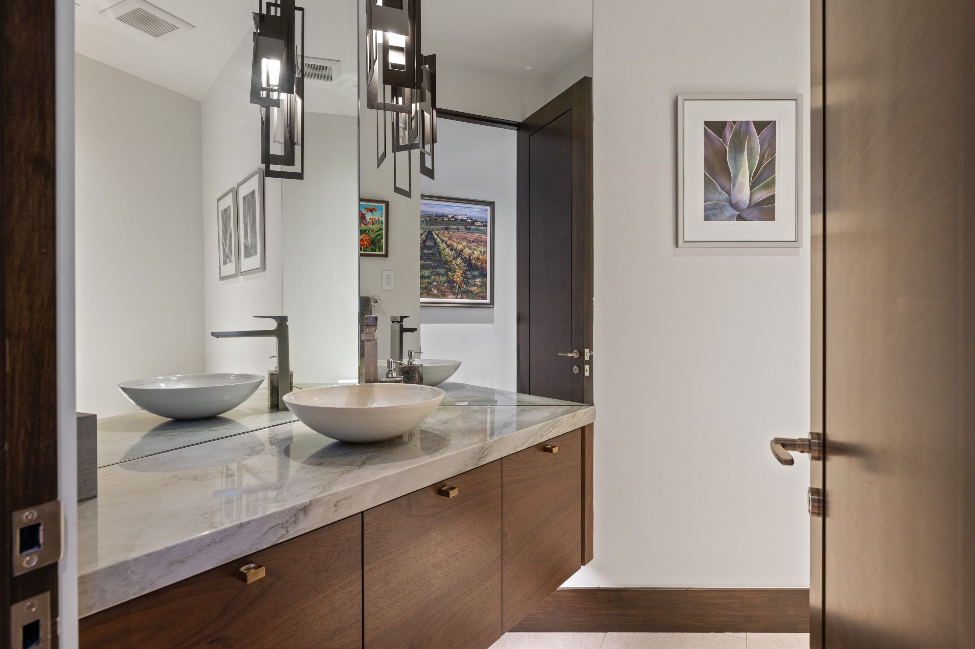 Floating vanity with integrated vessel sinks, wall-mounted faucets, and a light-toned stone countertop