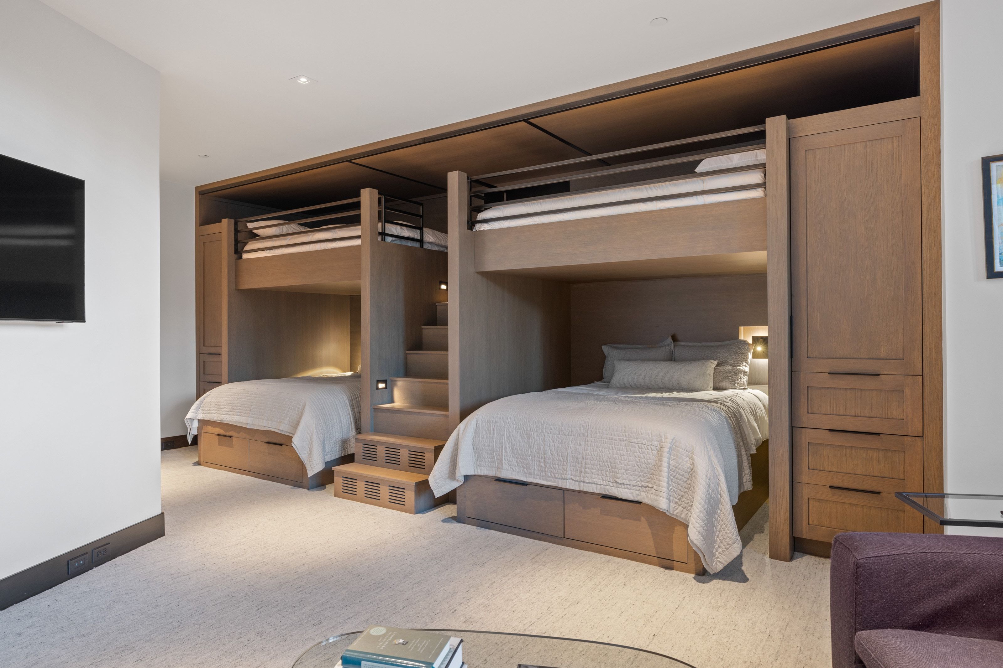 Custom built-in bunk beds featuring integrated shelving, under-bed storage drawers, and recessed lighting