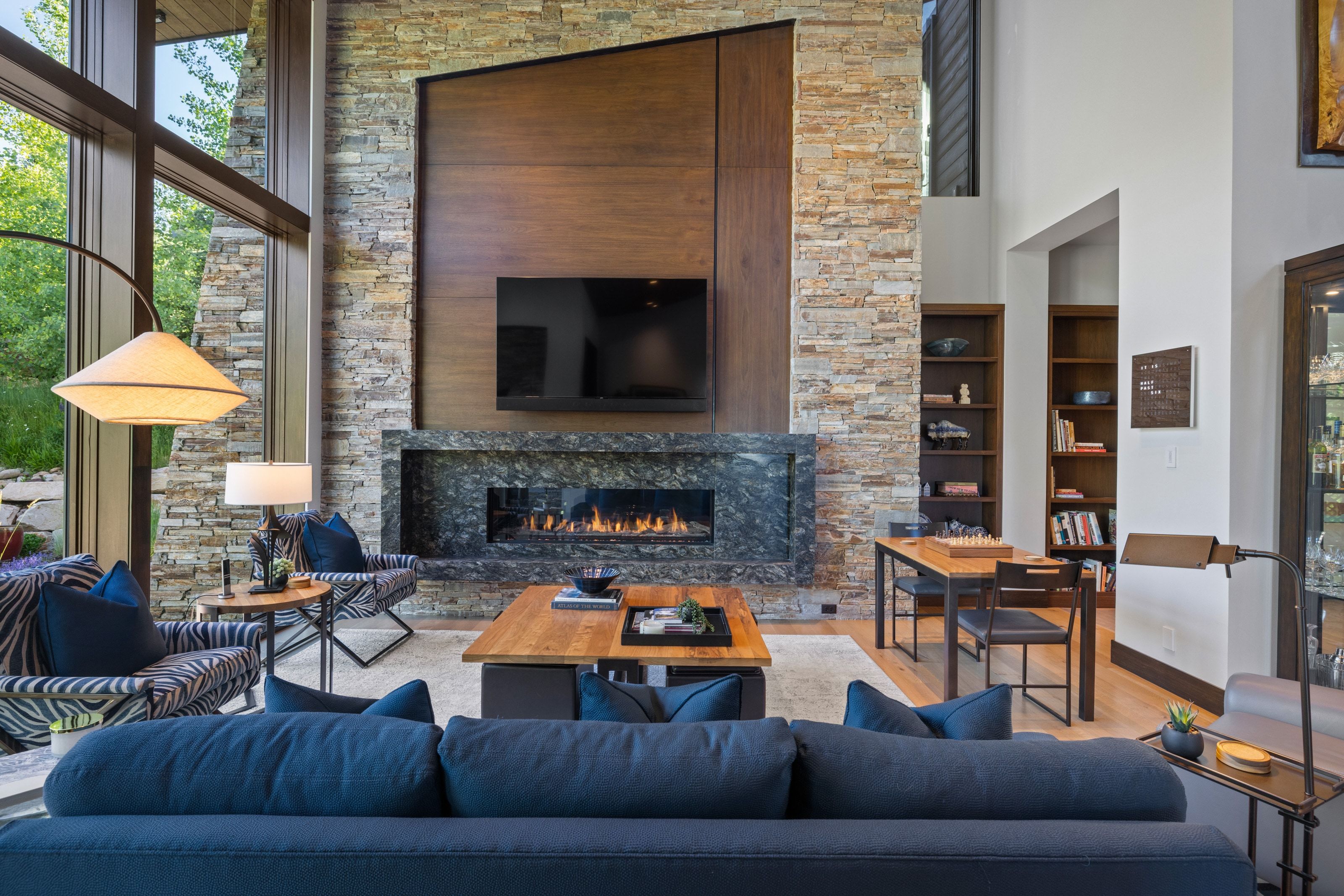 Grand living area featuring a floor-to-ceiling stone fireplace with a horizontal gas insert and a dark stone surround