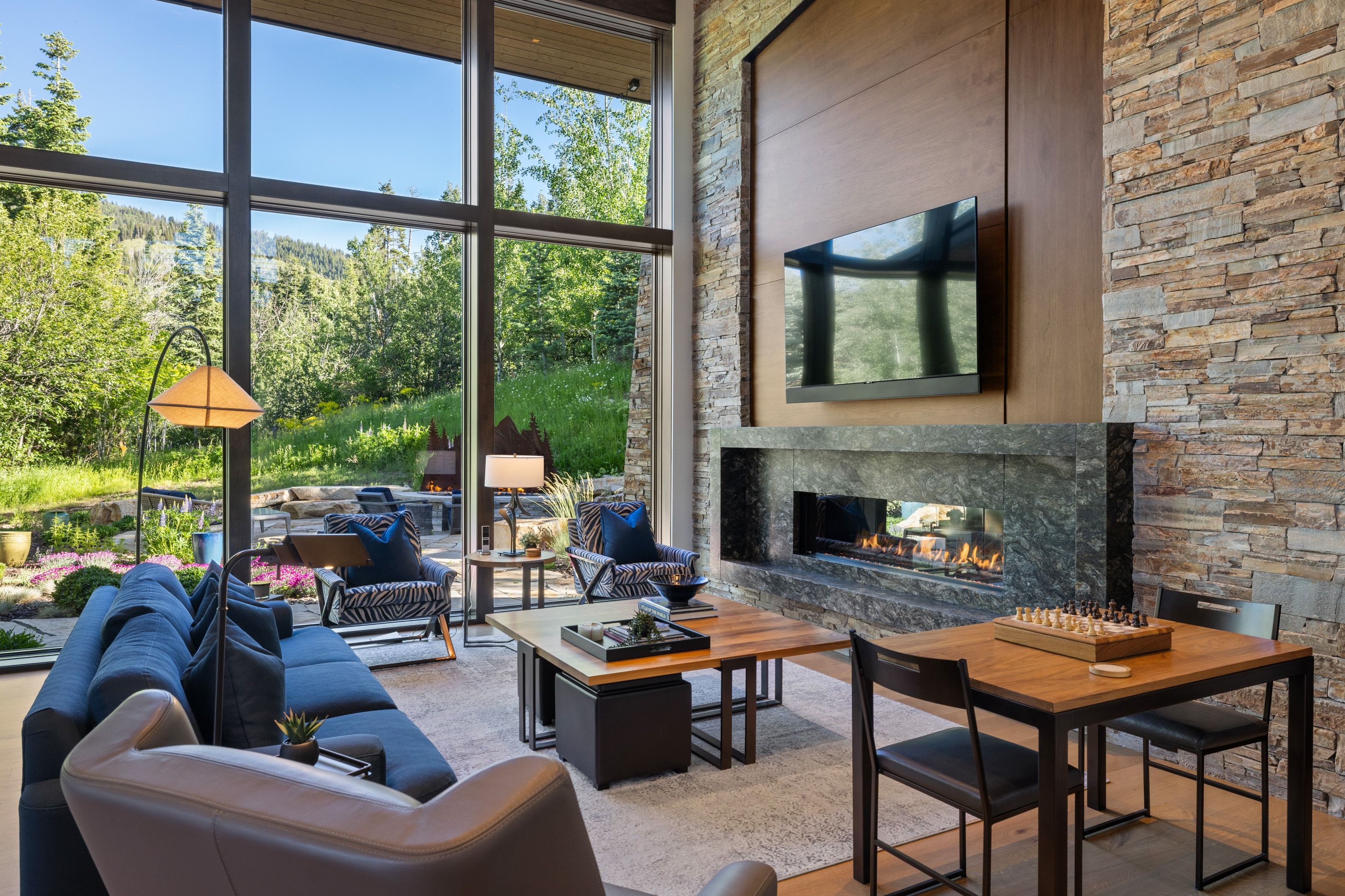 Spacious living area featuring floor-to-ceiling windows, a stone accent wall, an integrated linear fireplace, and wood-finish flooring