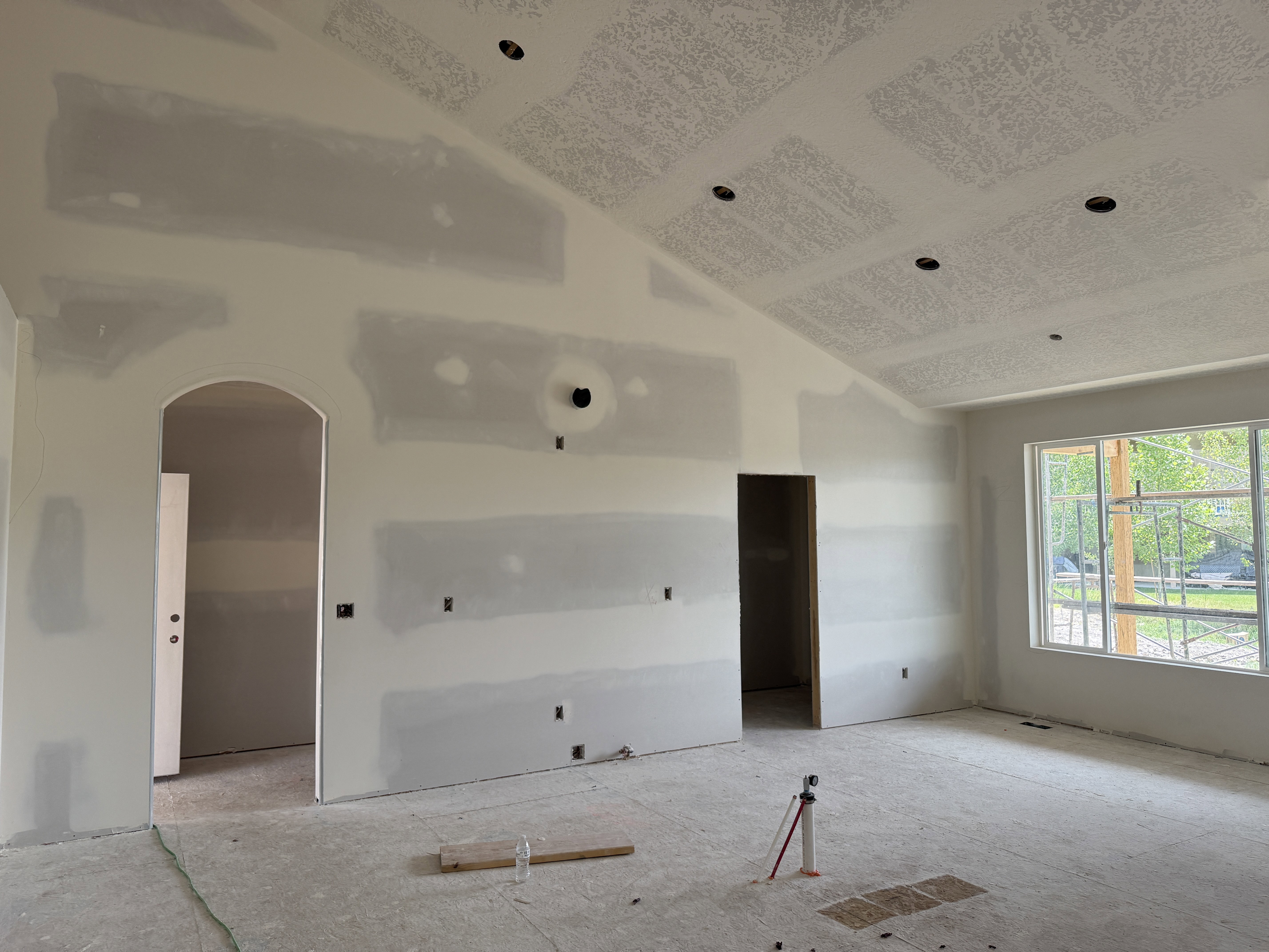 Spacious interior featuring a vaulted ceiling with recessed lighting, an arched doorway, and large windows