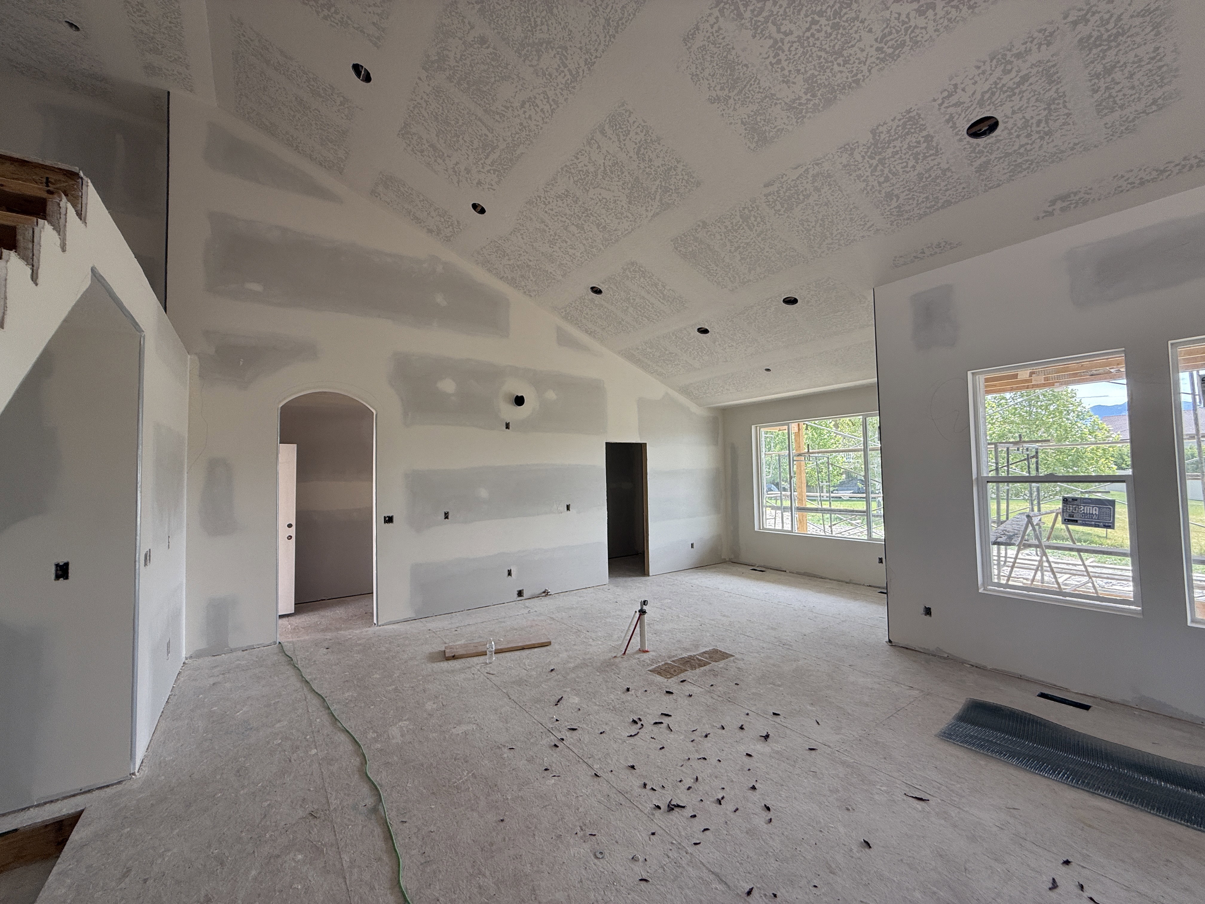 Expansive living area under construction featuring vaulted ceilings and recessed lighting