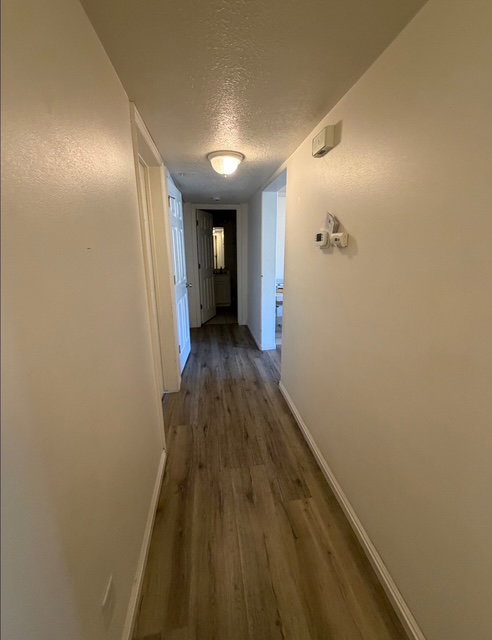 Hallway featuring wood-finish flooring and light-toned walls