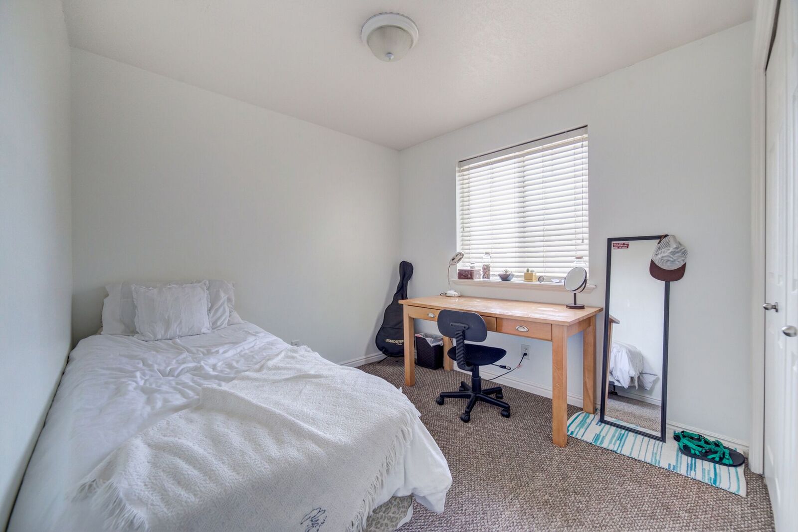 Carpeted room with a single window featuring horizontal blinds, a neutral wall color, and a flush-mount ceiling light fixture