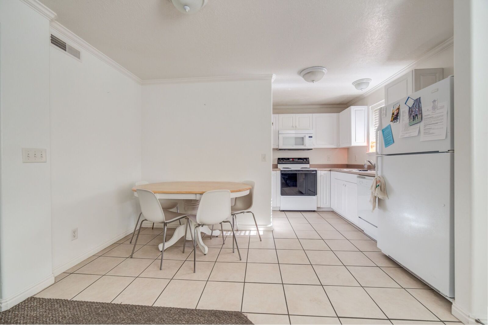 Kitchen and dining area featuring white cabinetry, white appliances, and tiled flooring
