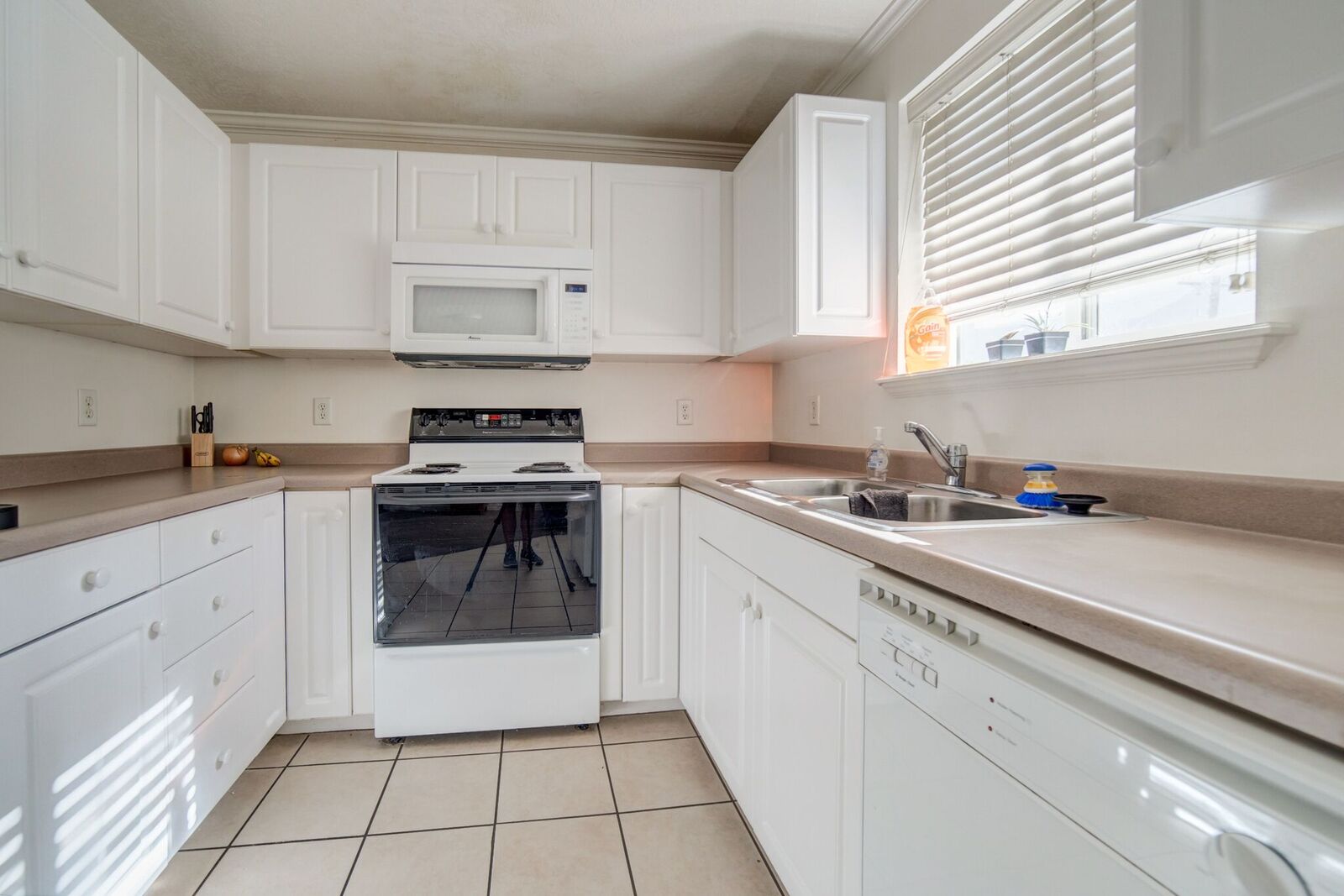 U-shaped kitchen featuring white cabinetry, light-toned countertops, and tile flooring
