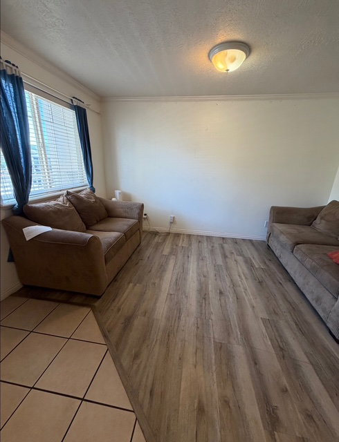 Spacious interior featuring wood-finish flooring, a neutral wall palette, crown molding, and an overhead flush-mount light fixture