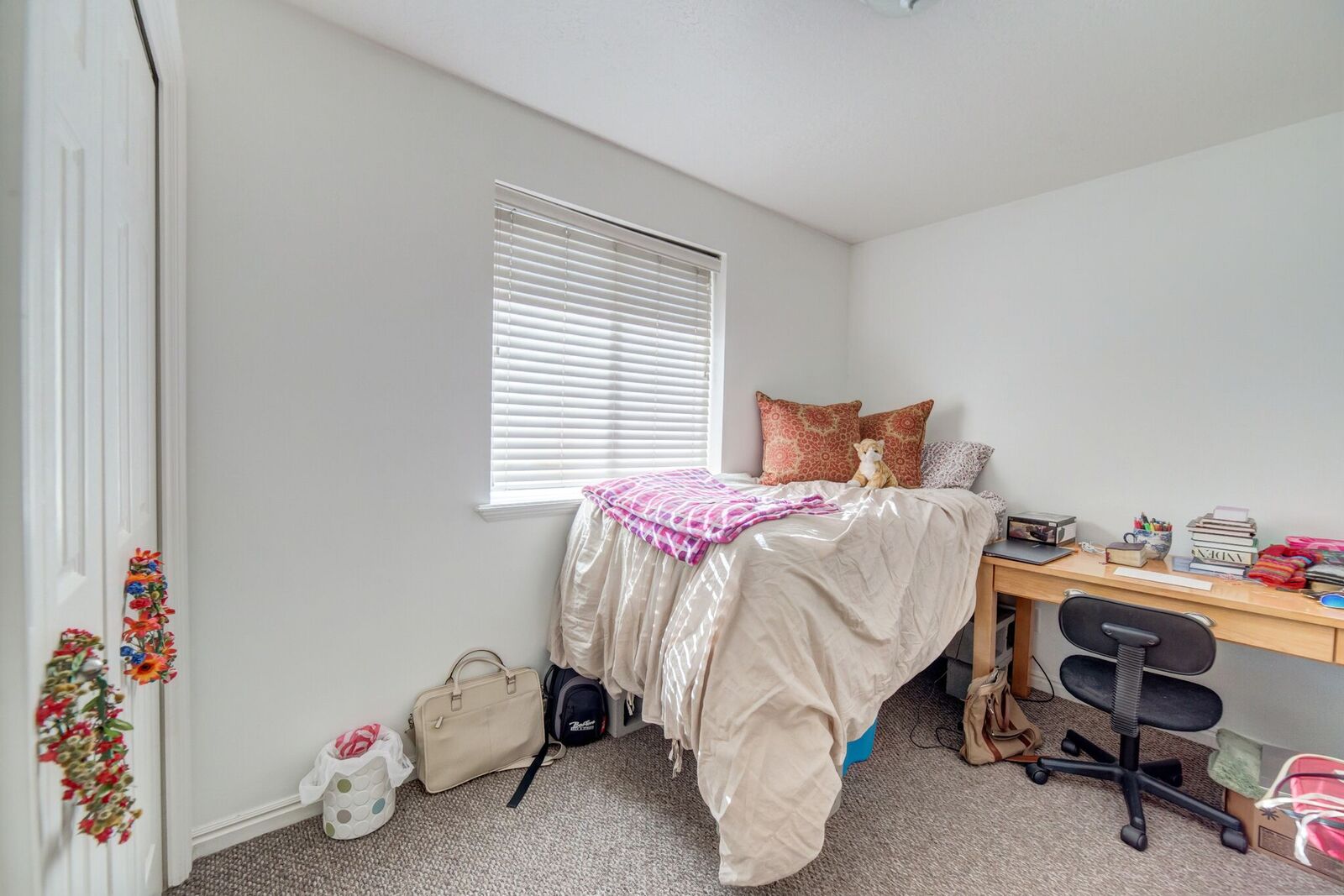 Bright room featuring a window with horizontal blinds, neutral wall paint, and gray carpet flooring