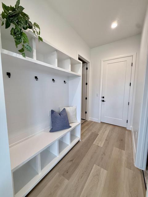 Entryway featuring a built-in white storage bench with cubbies, overhead shelving, and wall-mounted hooks