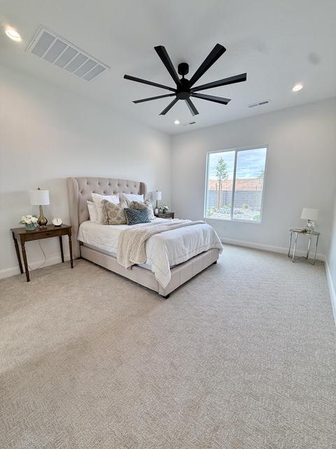Spacious room featuring neutral carpeting, a large window, a multi-blade ceiling fan, and recessed lighting