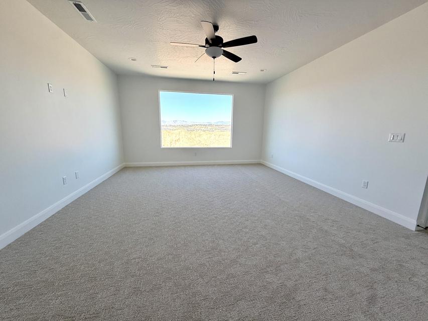 Spacious room featuring neutral carpeting, white walls, a large window, a ceiling fan, and recessed lighting