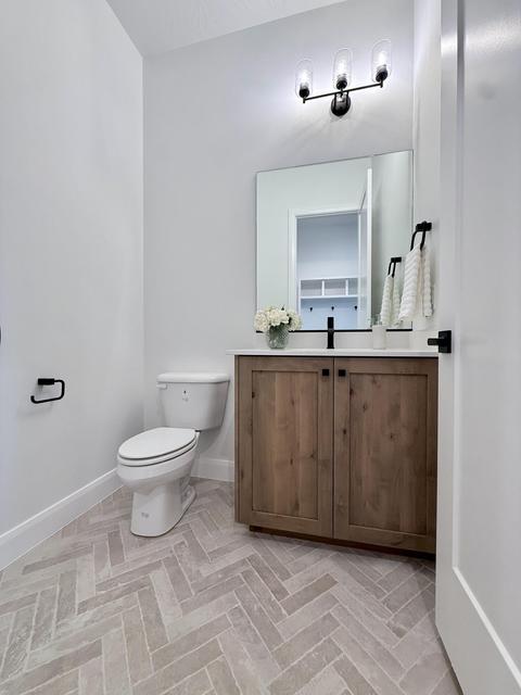 Bathroom featuring a wood-finish vanity with a black countertop, modern black fixtures, and a rectangular mirror