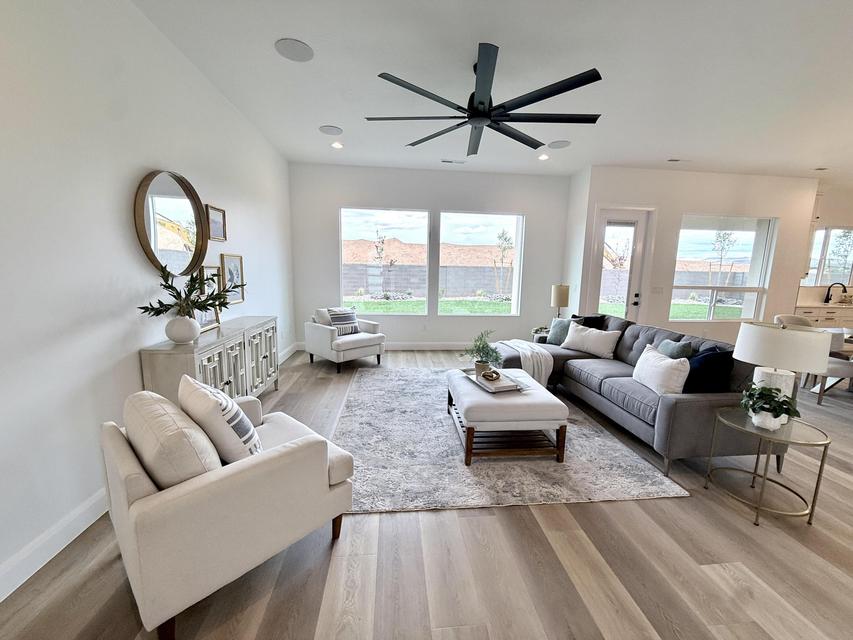Open-concept living area featuring wood-finish flooring, a large ceiling fan with multiple blades, recessed lighting, and multiple windows