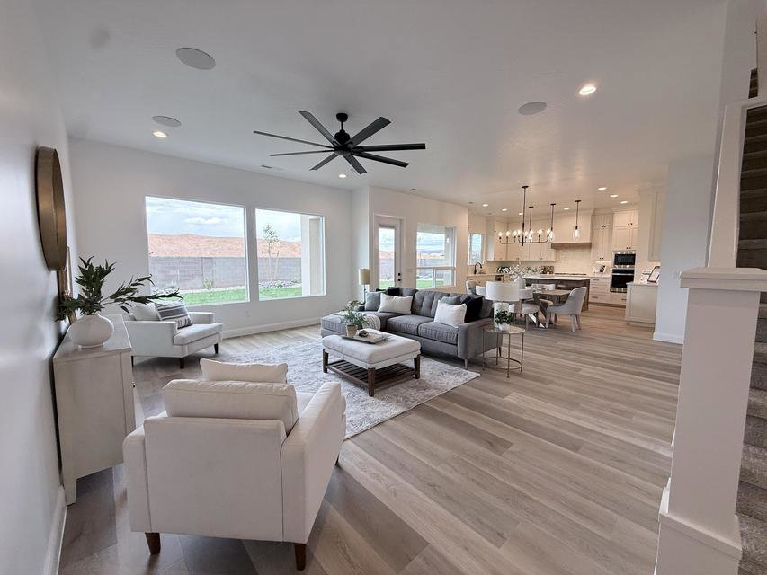 Spacious open-concept living area featuring light wood-finish flooring, a large ceiling fan, and recessed lighting