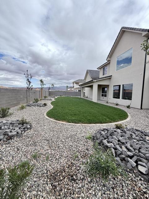 Expansive backyard featuring a manicured lawn, gravel landscaping, and decorative rock elements