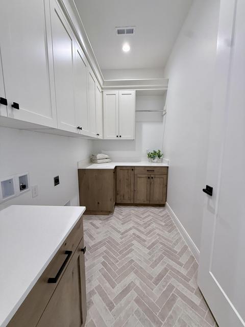 Herringbone tile flooring defines this laundry space, complemented by extensive white cabinetry with matte black hardware
