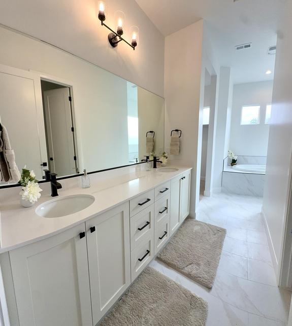 Dual vanity with white cabinetry, quartz countertop, and matte black fixtures