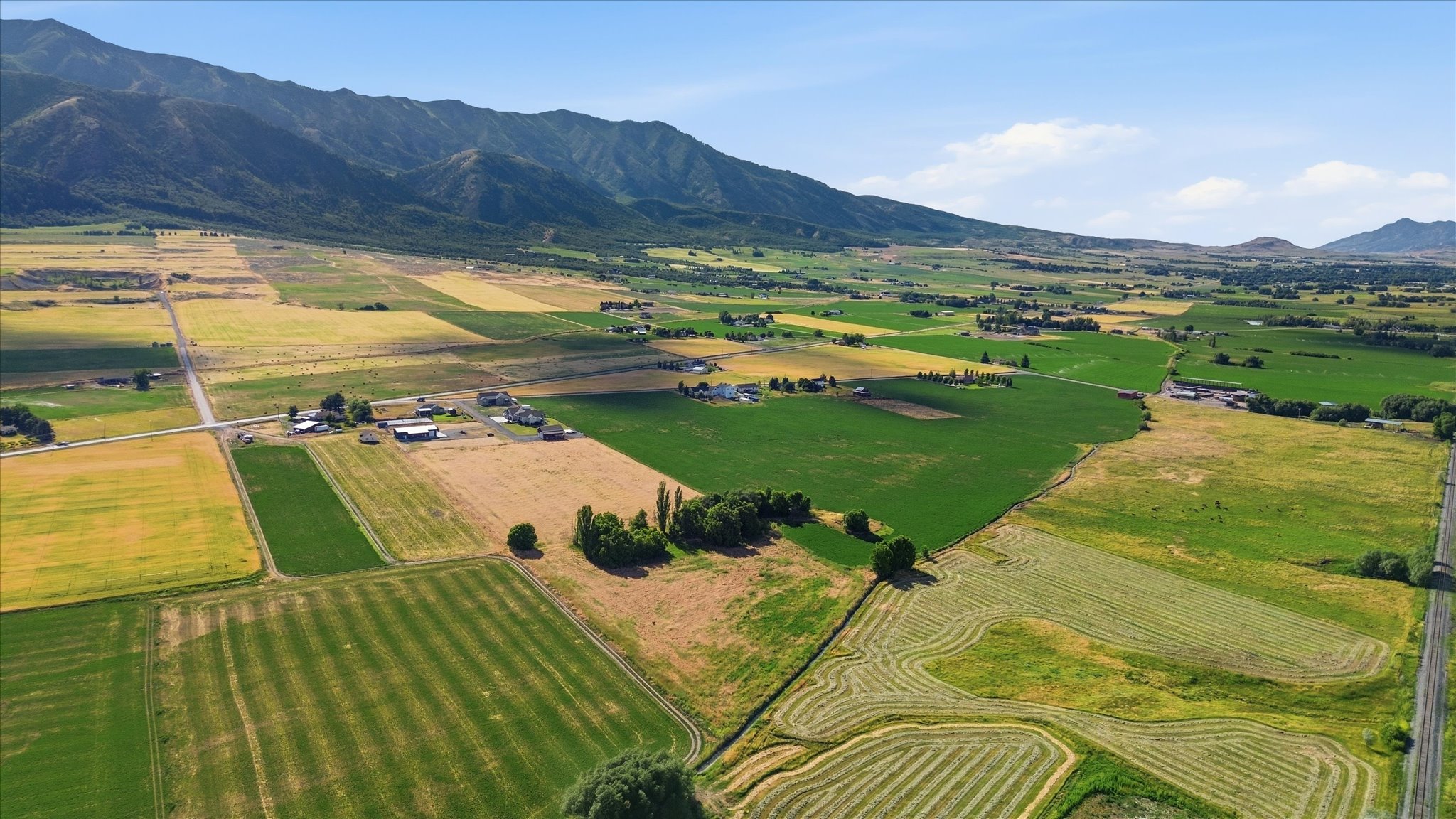 Expansive agricultural land featuring diverse crop fields and mountainous terrain