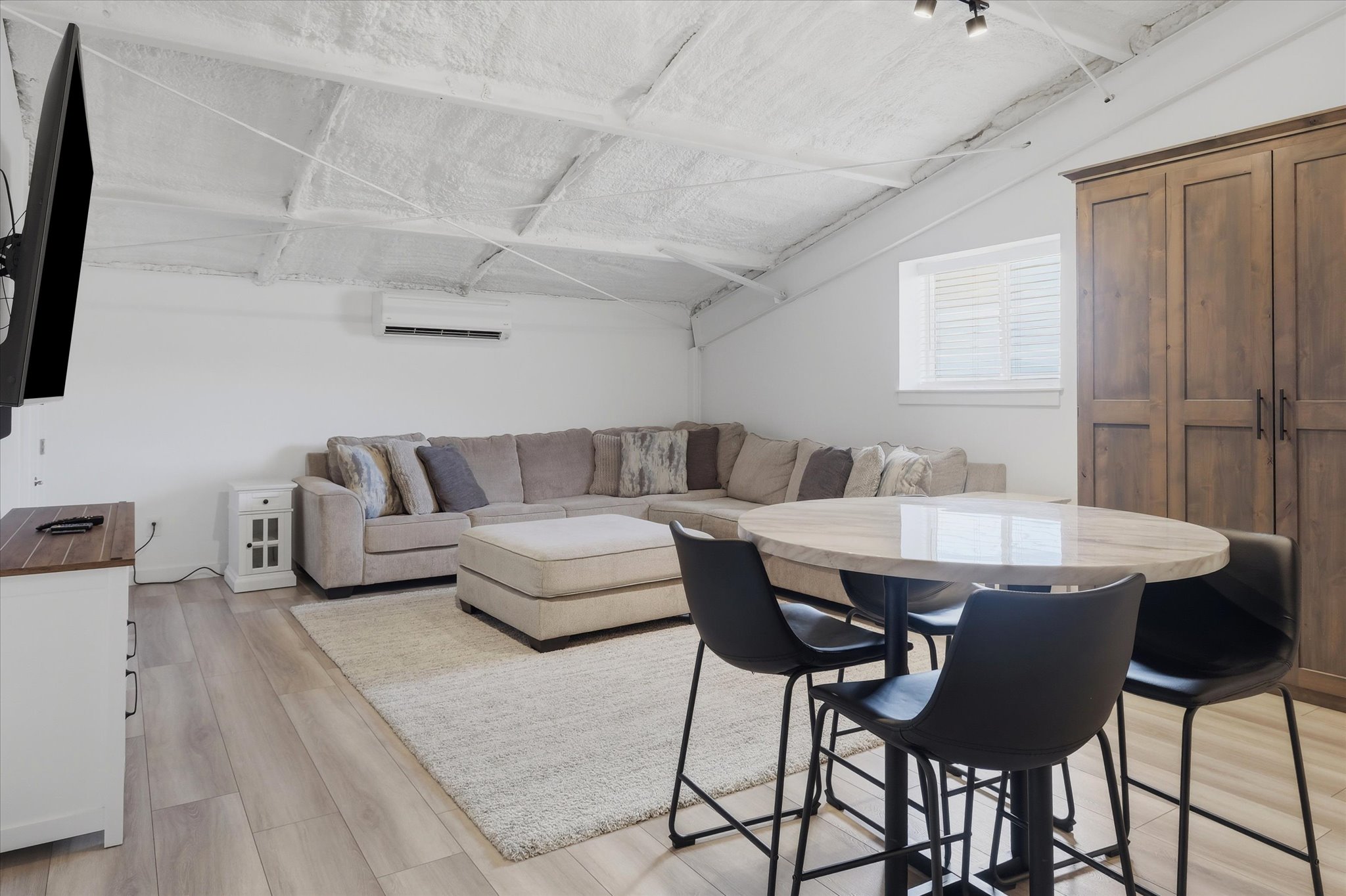 Spacious room featuring wood-finish flooring, white walls, and a textured white ceiling