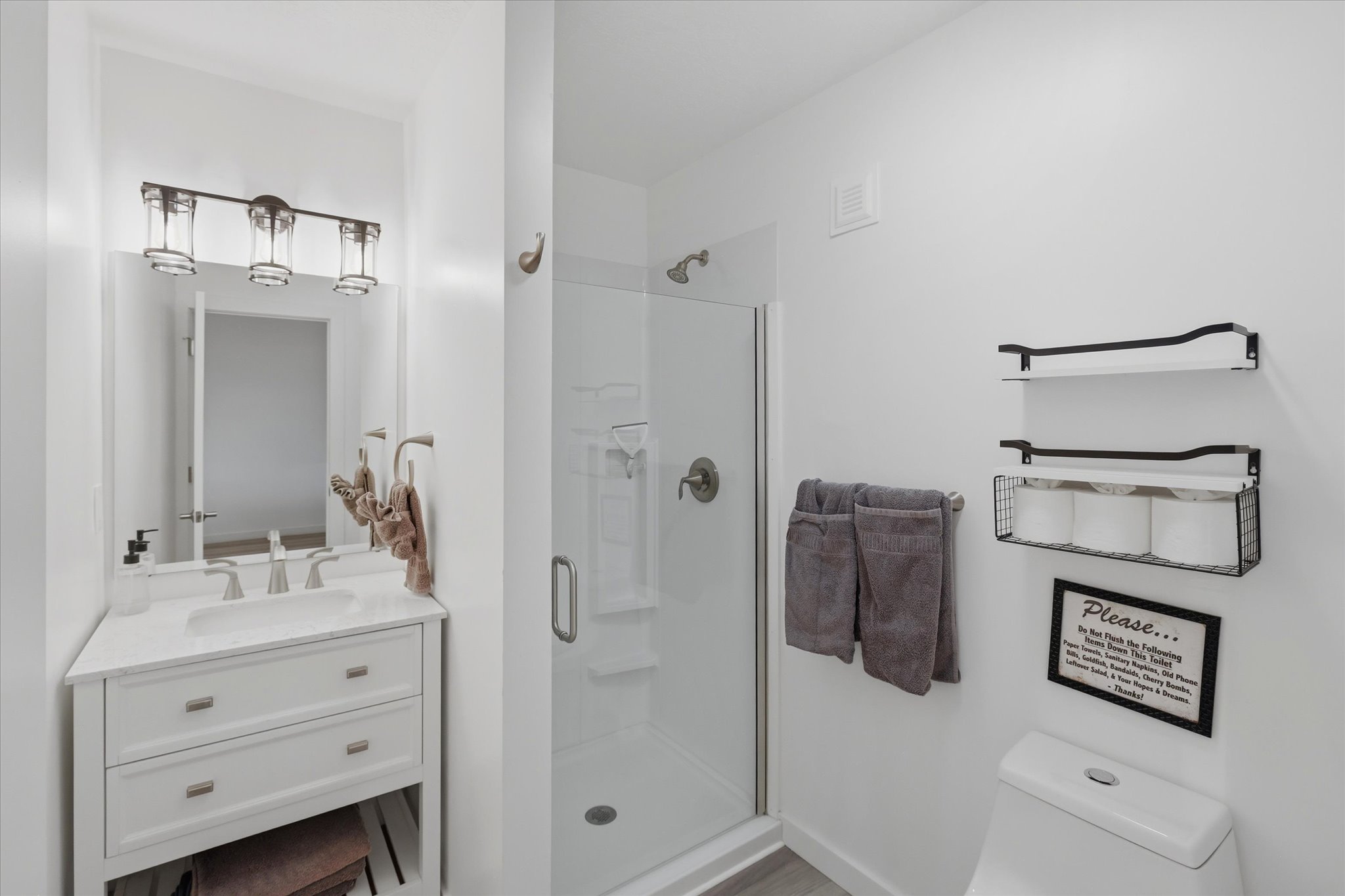 Full bathroom featuring a white vanity with a recessed sink, brushed nickel faucet, and a frameless mirror